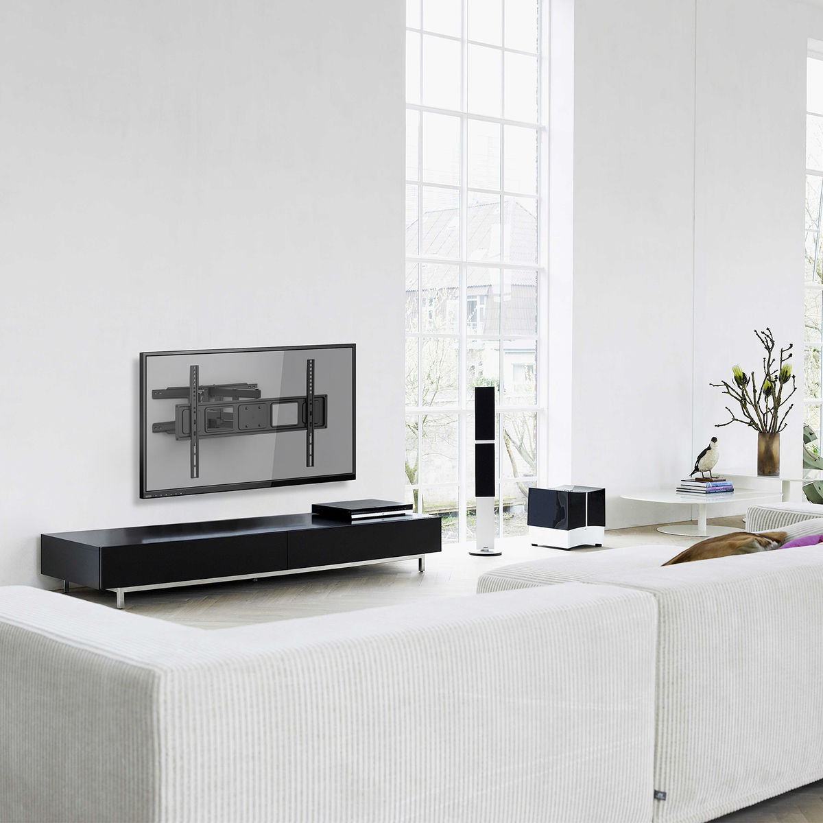 Una sala de estar moderna con un televisor montado y un armario negro. Hay un sofá blanco y una ventana grande.