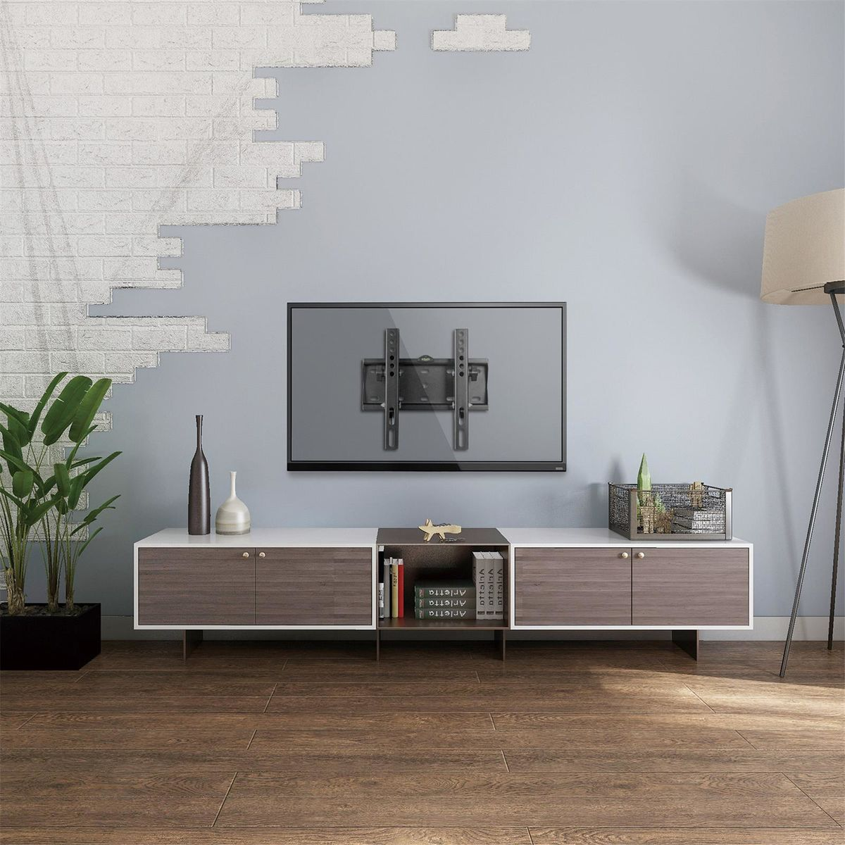 Tv gemonteerd boven een witte kast, met decoratie zoals een plant en boeken.
