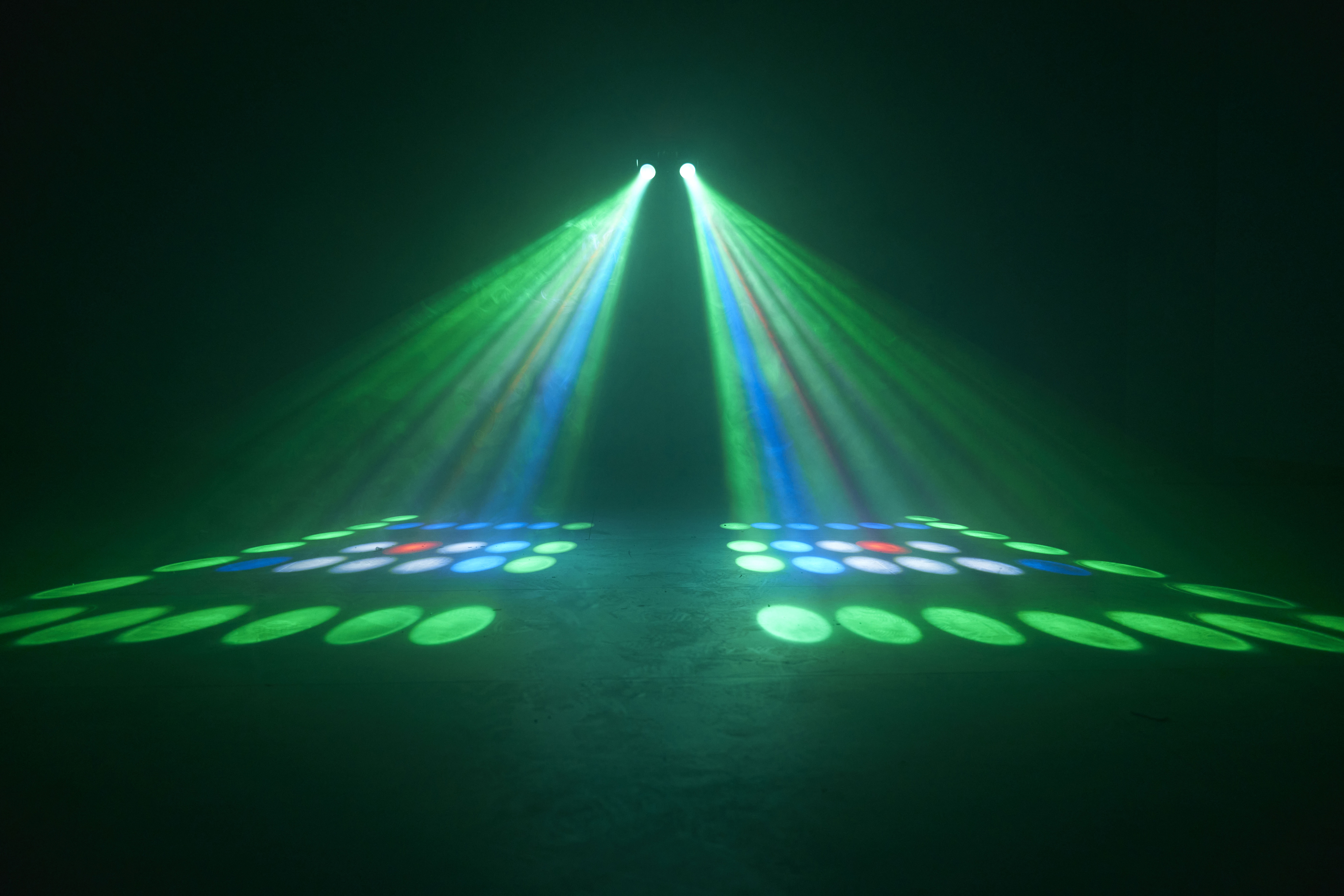 A dark stage with green and blue spotlights. The lights illuminate the stage.