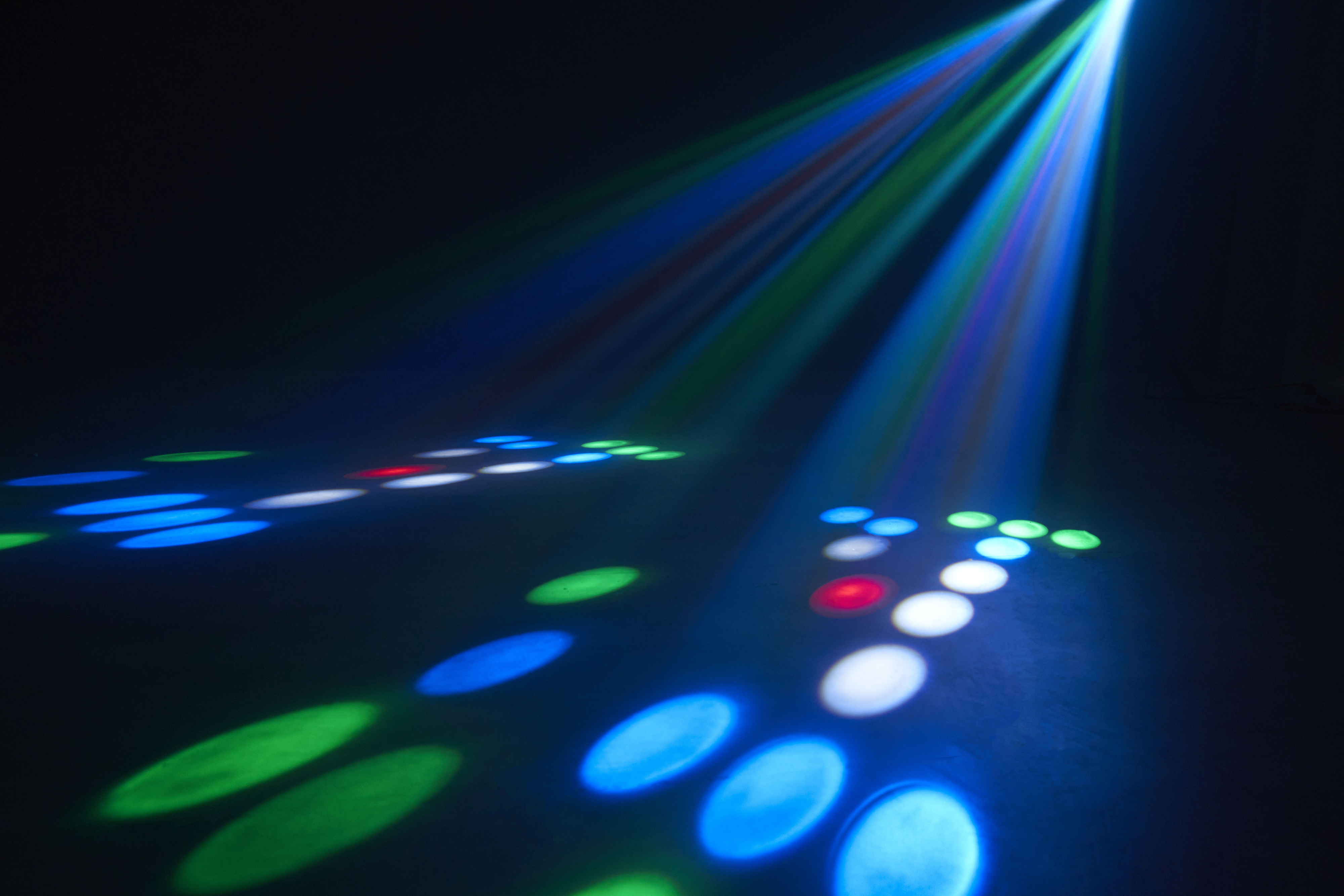 Stage lights with blue and green beams shining on the floor. Dots of light.