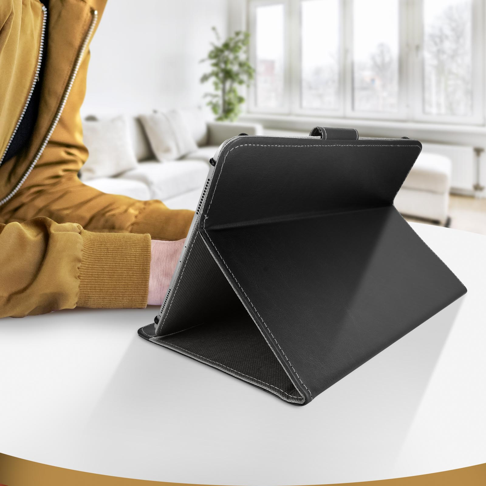 Custodia per tablet nera aperta su un tavolo bianco. Persona sullo sfondo. Soggiorno.