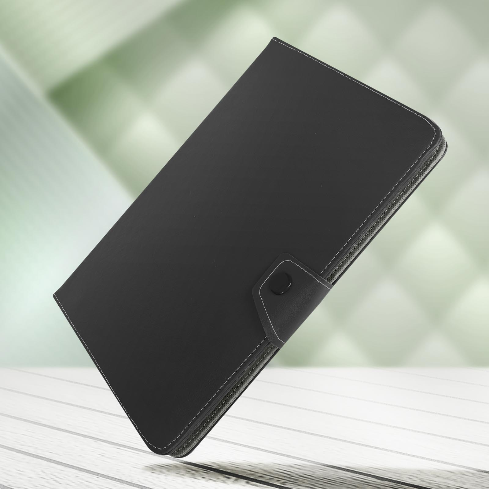 Custodia nera per tablet con cuciture bianche, chiusa, angolata su una superficie di legno chiaro.