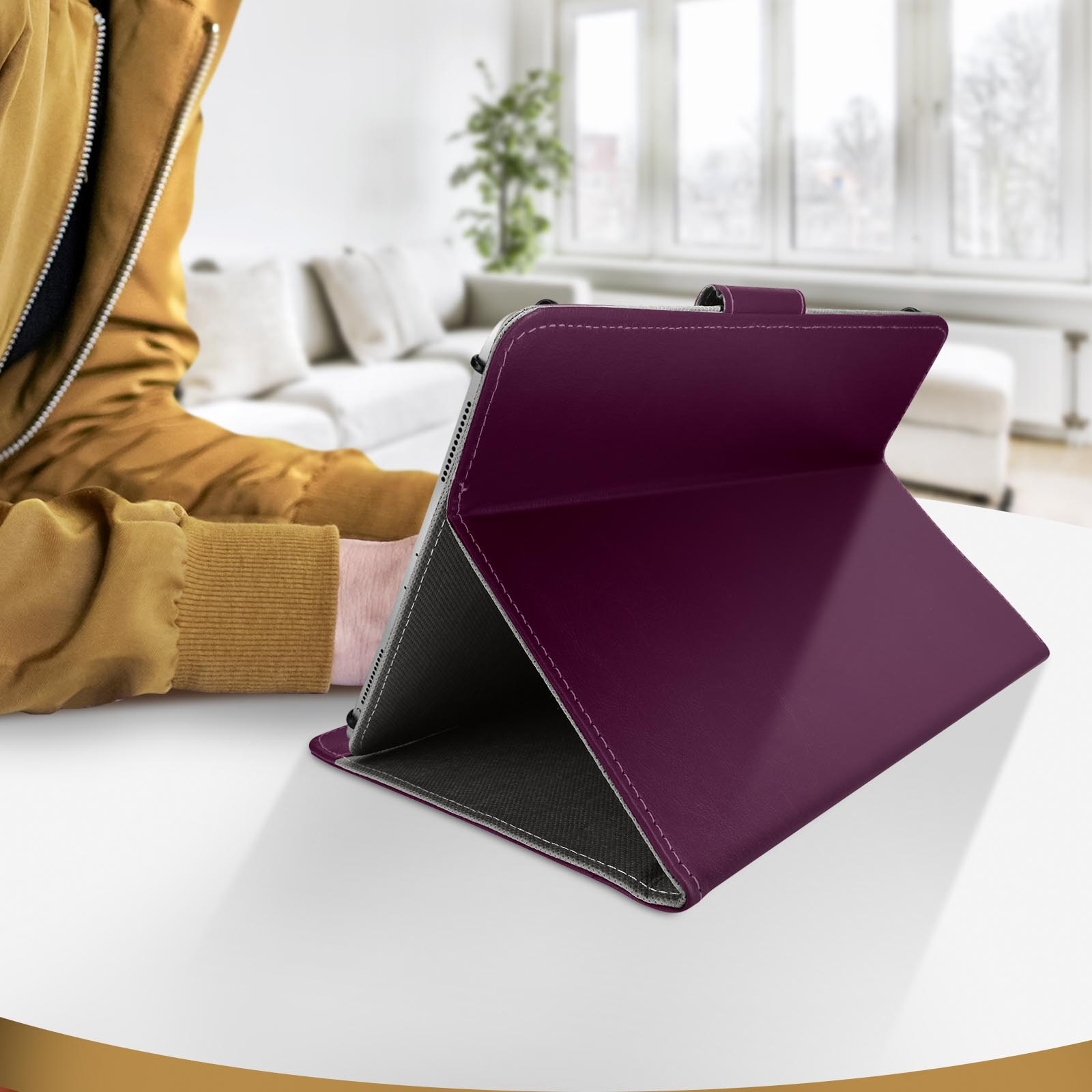 Un tablet in una custodia viola su un tavolo bianco. Una persona sfocata sullo sfondo.