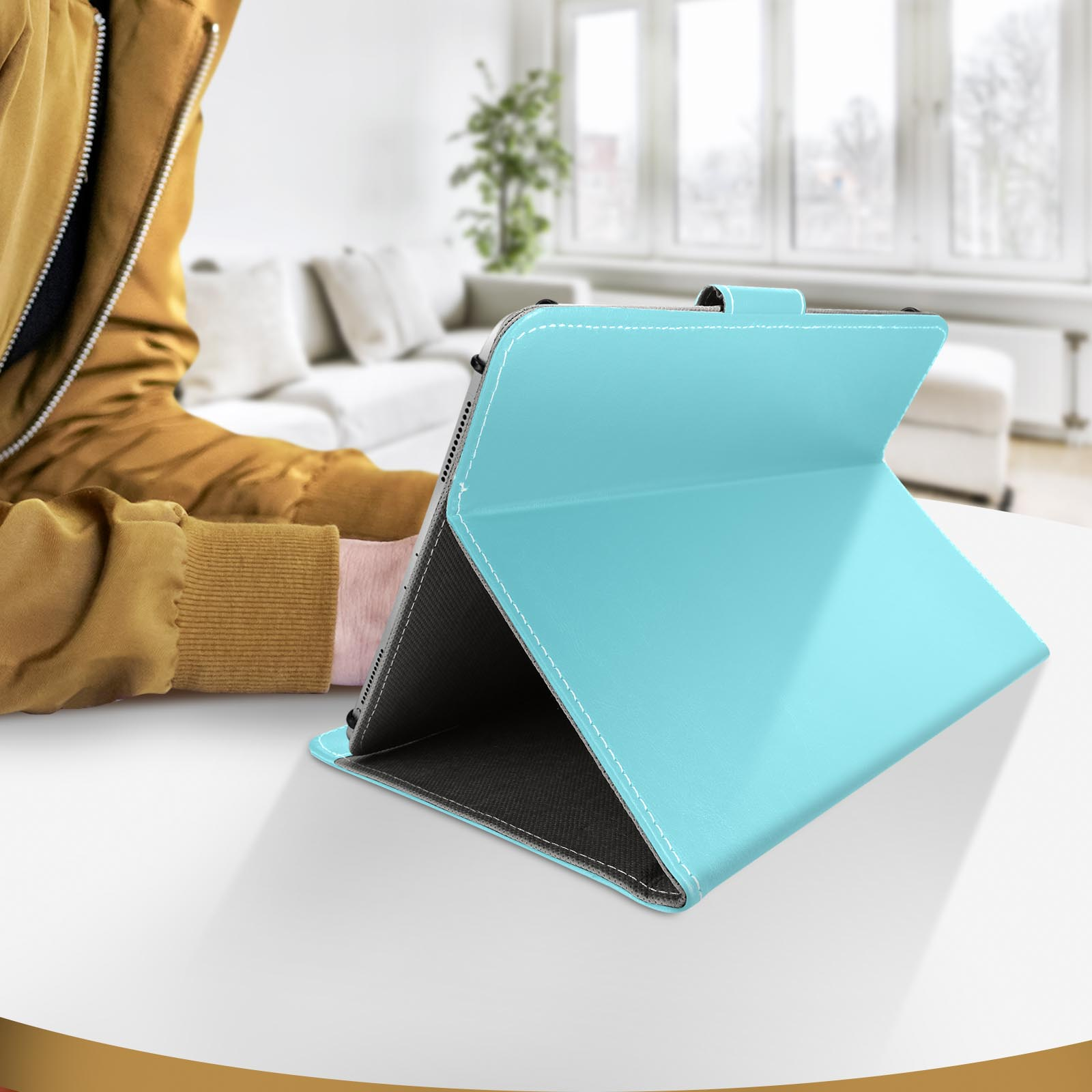 Una custodia per tablet azzurra aperta su un tavolo bianco. Una persona è seduta sullo sfondo.