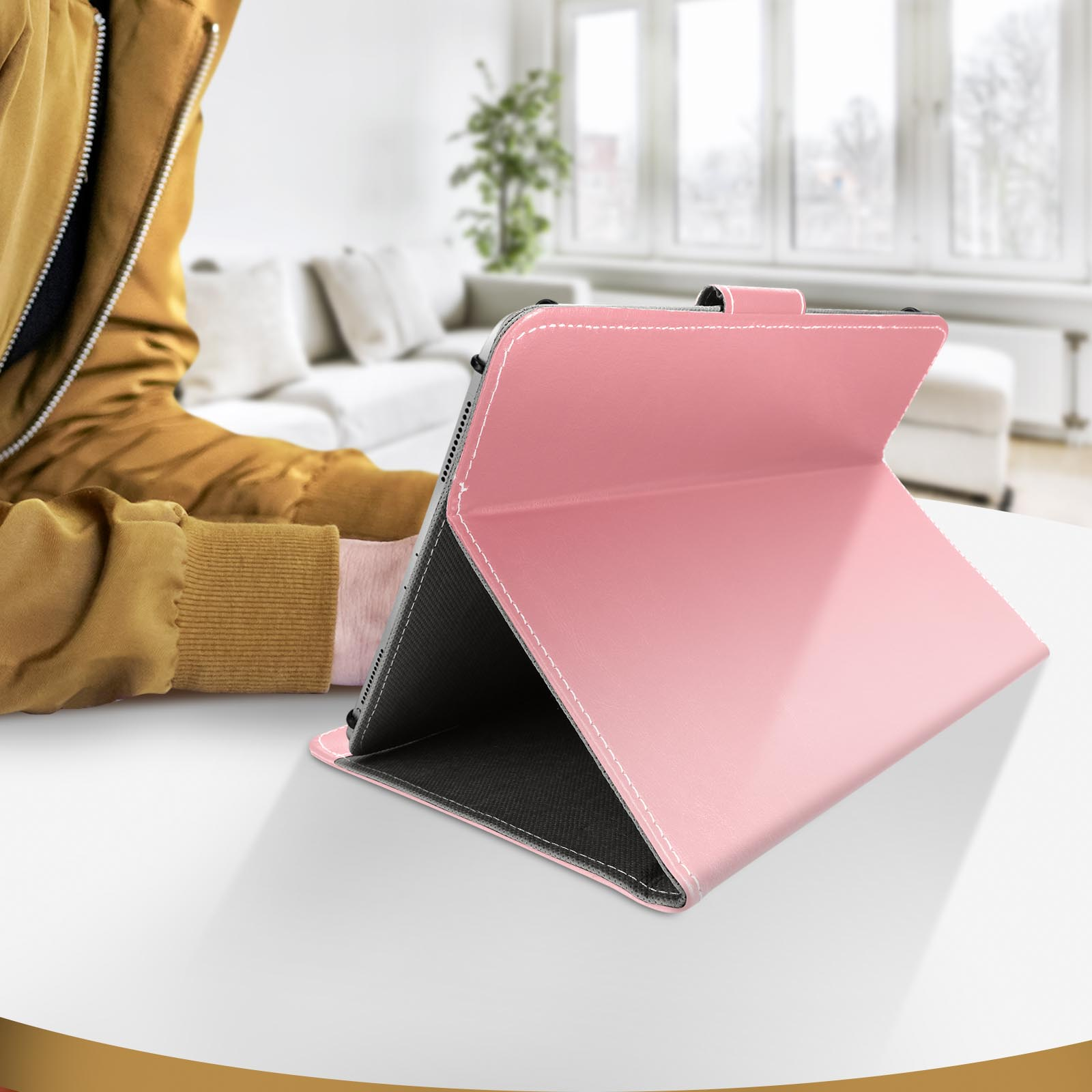 Custodia rosa per tablet aperta su un tavolo bianco. Una persona è seduta vicino.