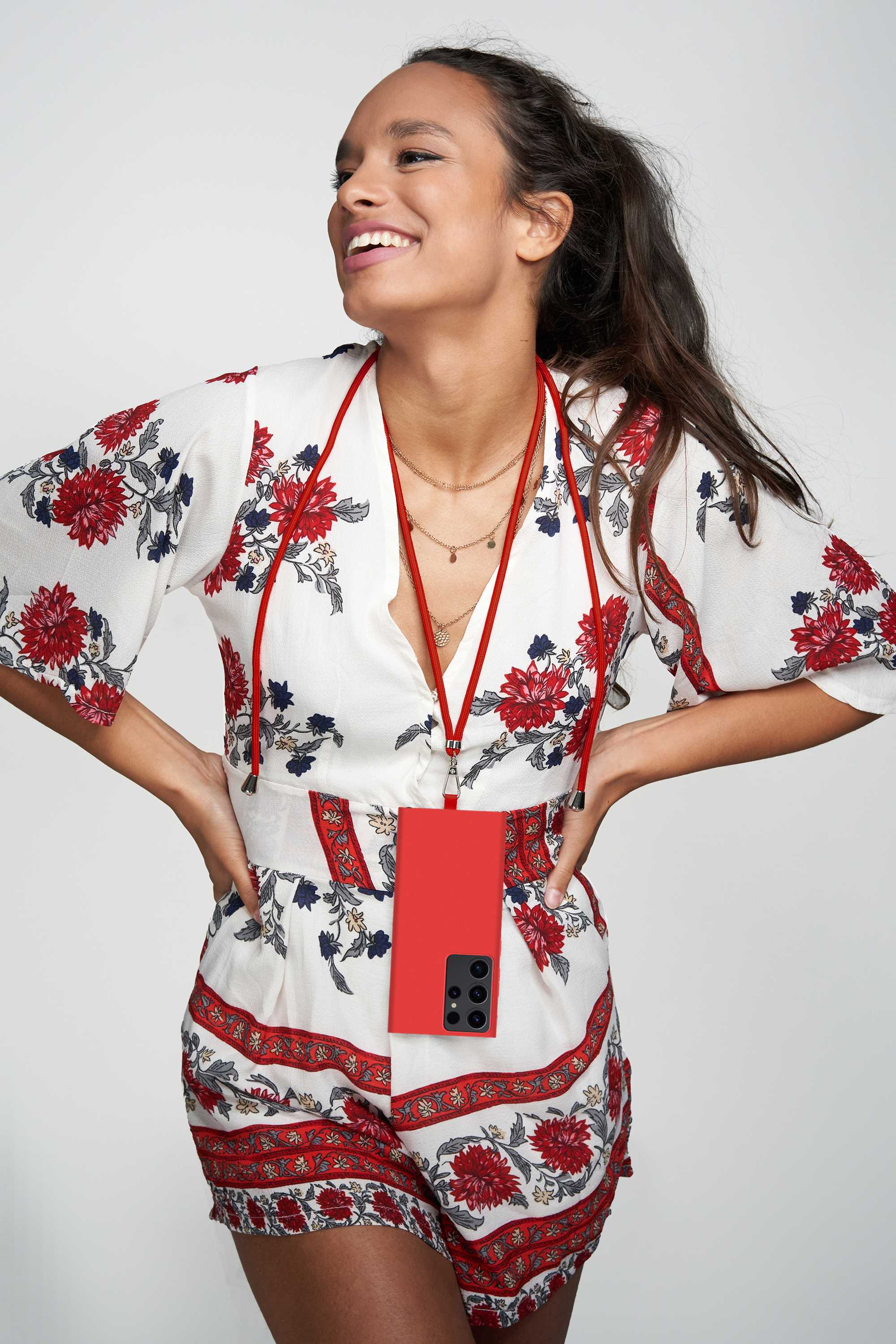 Frau in weißem Blumen-Outfit, hält rotes Telefon mit rotem Umhängeband.