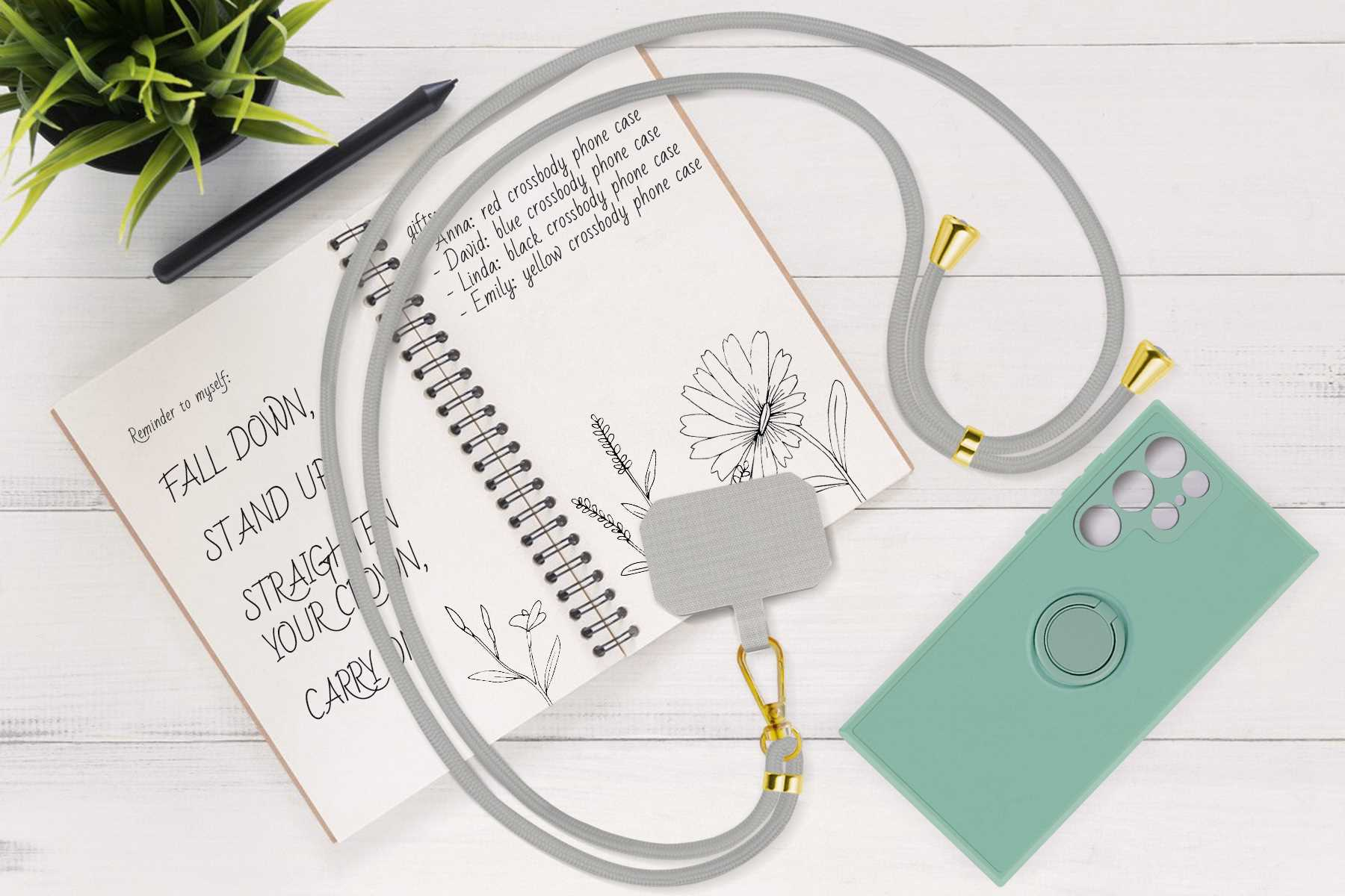 Graues Handy-Lanyard mit Handyhülle und Notizblock mit Text und Blumen auf dem Schreibtisch.