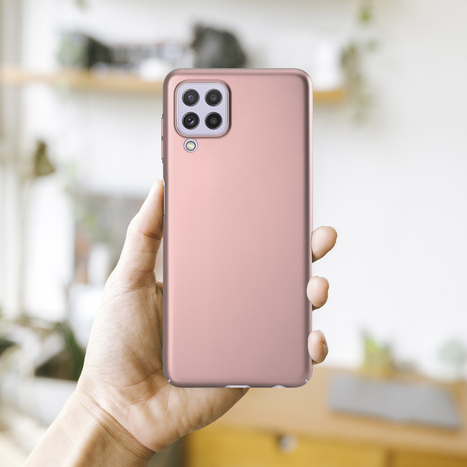 Hand, die eine rosa Handyhülle mit Kamerahöckern hält, verschwommener Hintergrund.