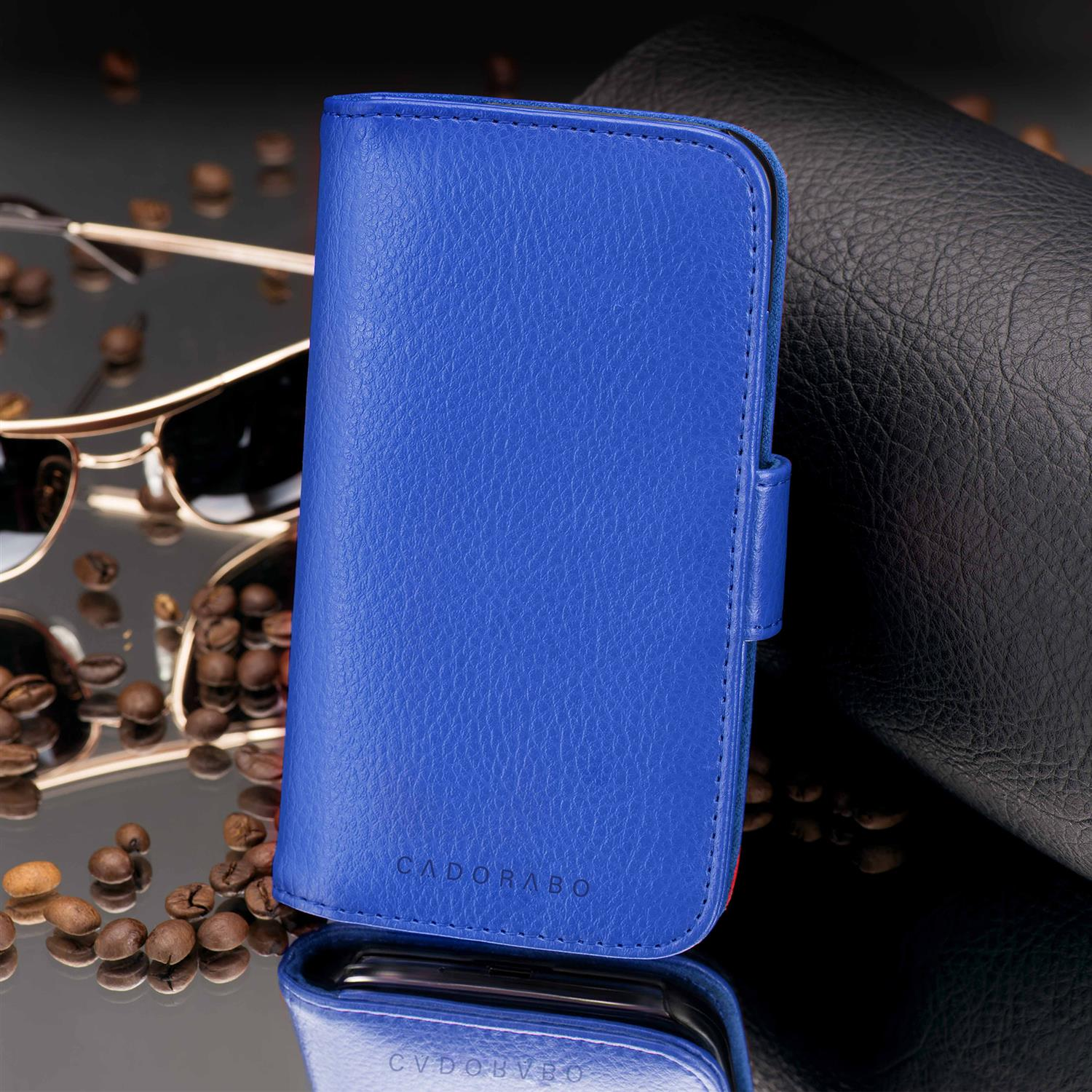 Blaue Leder-Handyhülle mit geschlossenem Deckel, braunen Kaffeebohnen und einer Sonnenbrille.