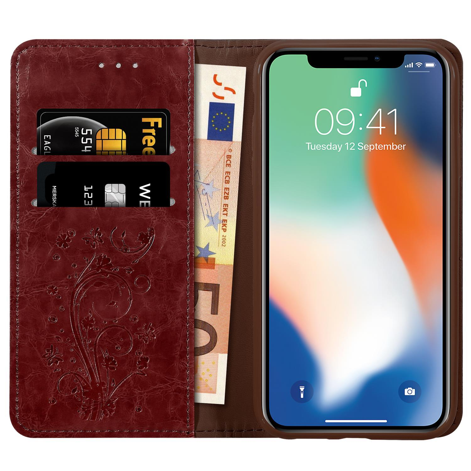 Eine weinrote Handyhülle mit Telefon und Karten. Das Telefon zeigt die Uhrzeit.