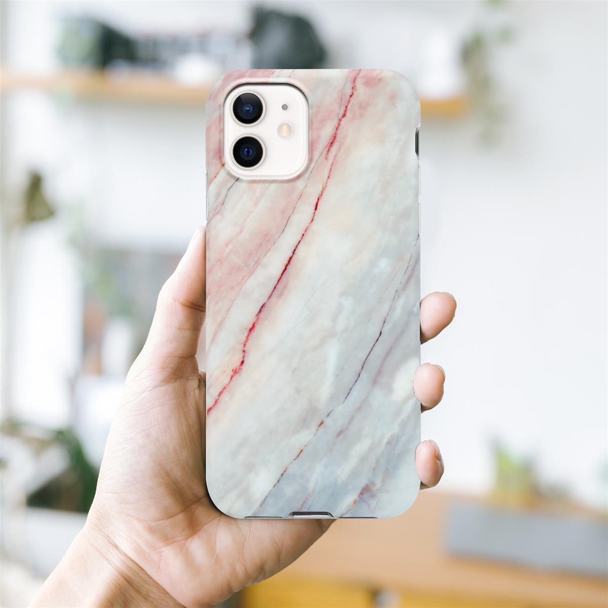 Eine Hand hält eine Handyhülle mit Marmordesign und ein Telefon darin.