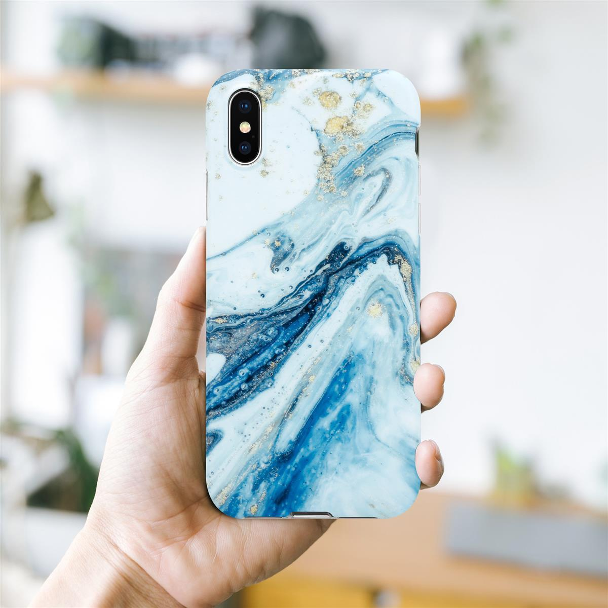 Mano che tiene un telefono con una custodia dal design in marmo blu e oro. Sfondo sfocato.