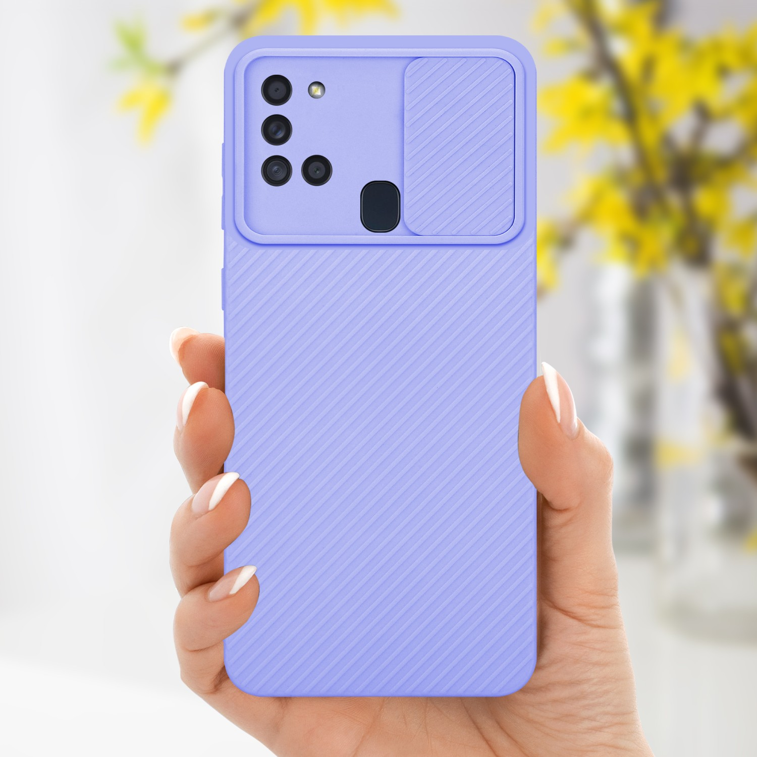 Hand hält eine hellviolette Handyhülle mit Kameraabdeckung. Gelbe Blumen sind im Hintergrund.