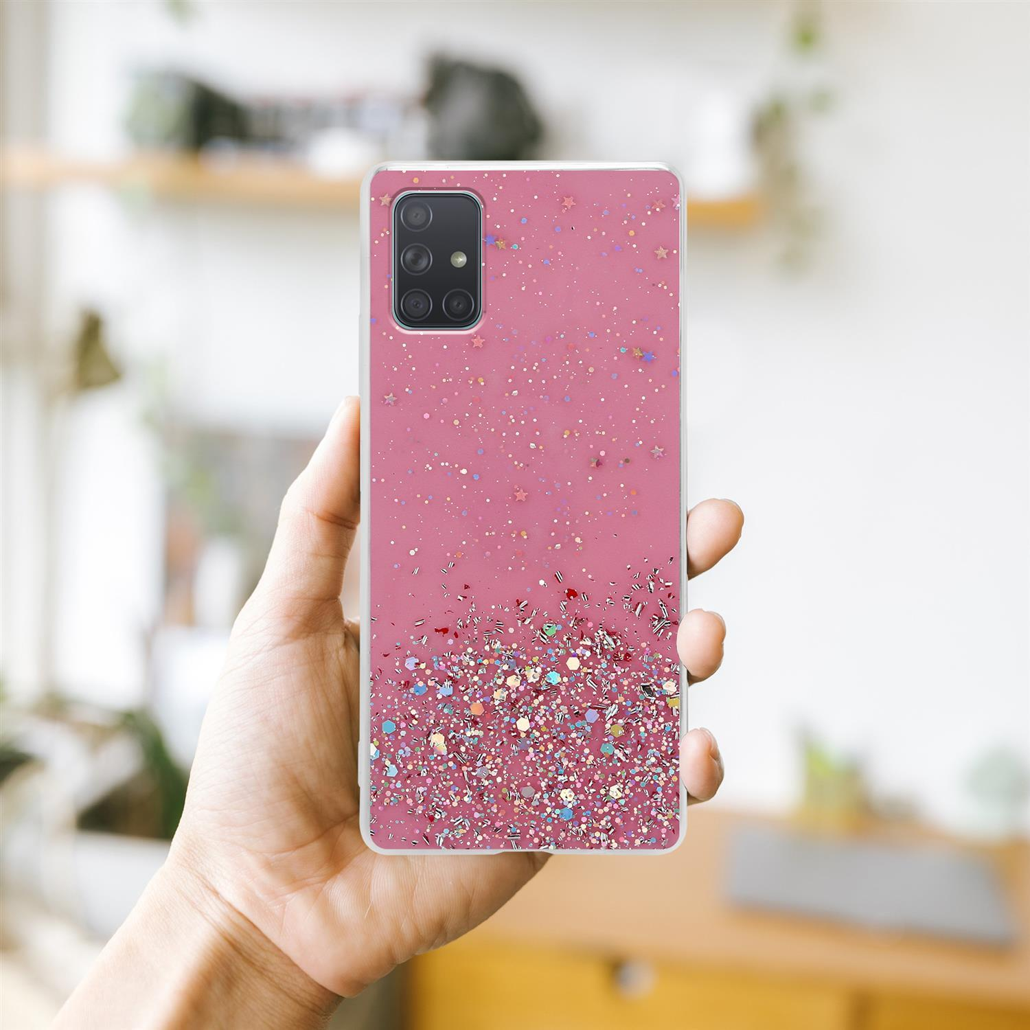 Eine Hand hält eine pinkfarbene Handyhülle mit Glitzer. Der Hintergrund ist ein Raum mit weißen Wänden und einer Leuchte.