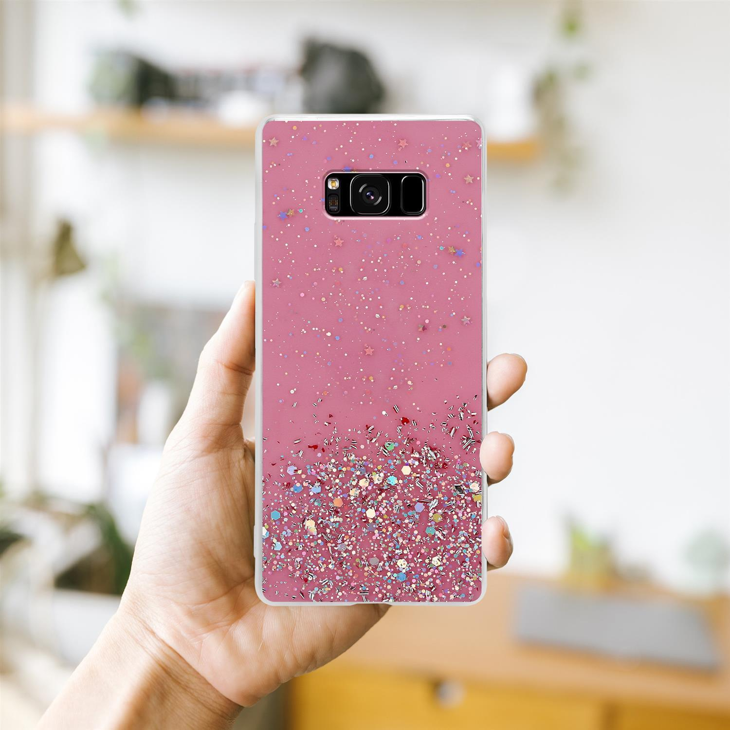 Rosa Handyhülle mit Glitzereffekt. Telefon in der Hand. Der Hintergrund ist ein verschwommener Raum.