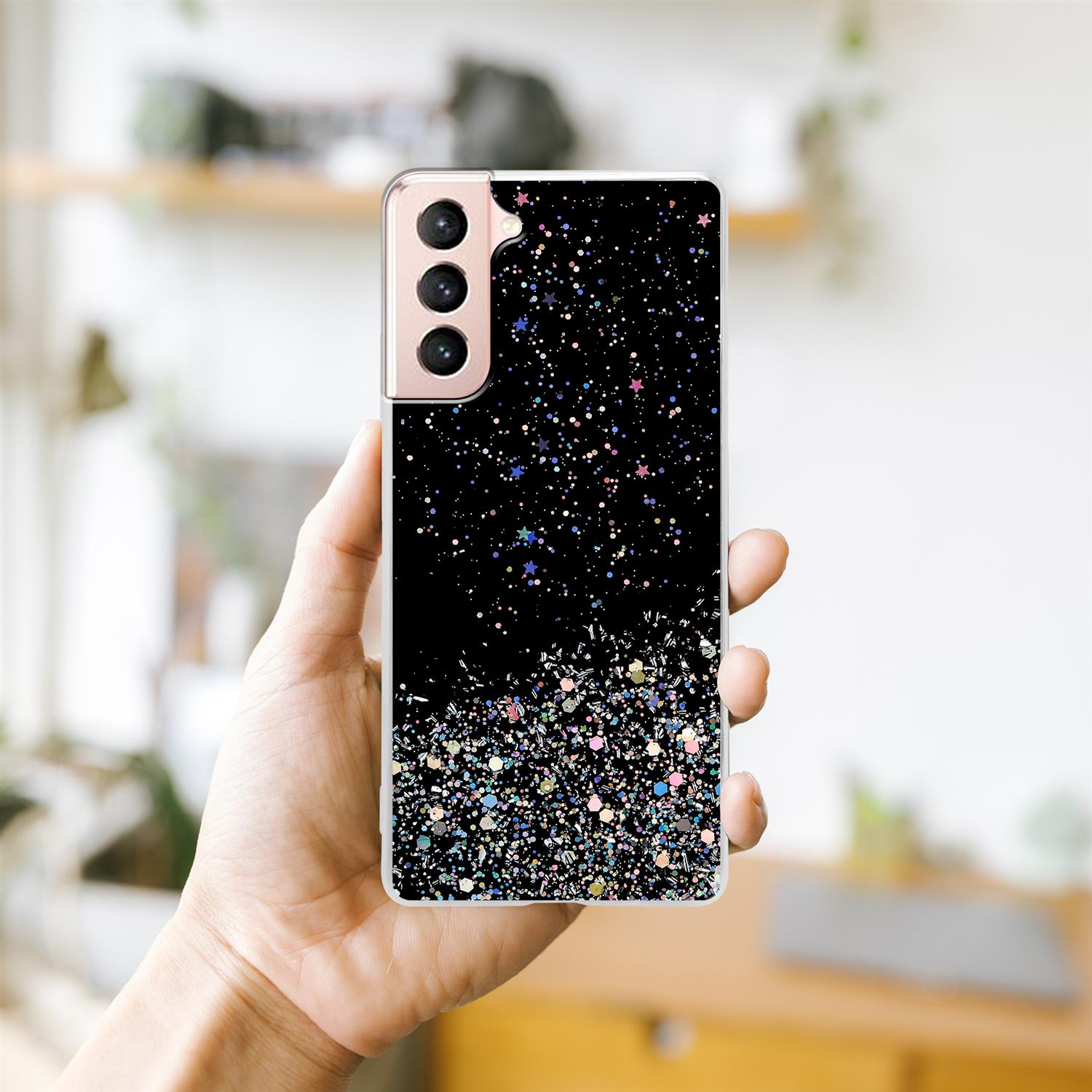 Hand hält eine schwarze Handyhülle mit Glitzer. Schwarzer Hintergrund mit Glitzer.