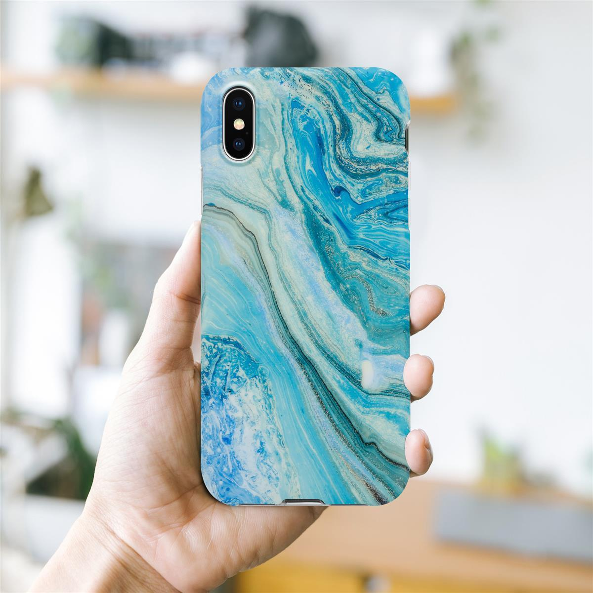 Una mano che tiene un telefono con una custodia effetto marmo blu e bianco, su uno sfondo sfocato.