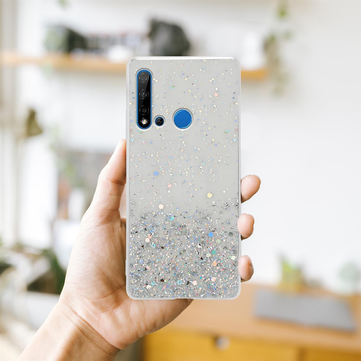 Eine Hand hält eine transparente Handyhülle mit Glitzer. Der Hintergrund ist ein Regal.