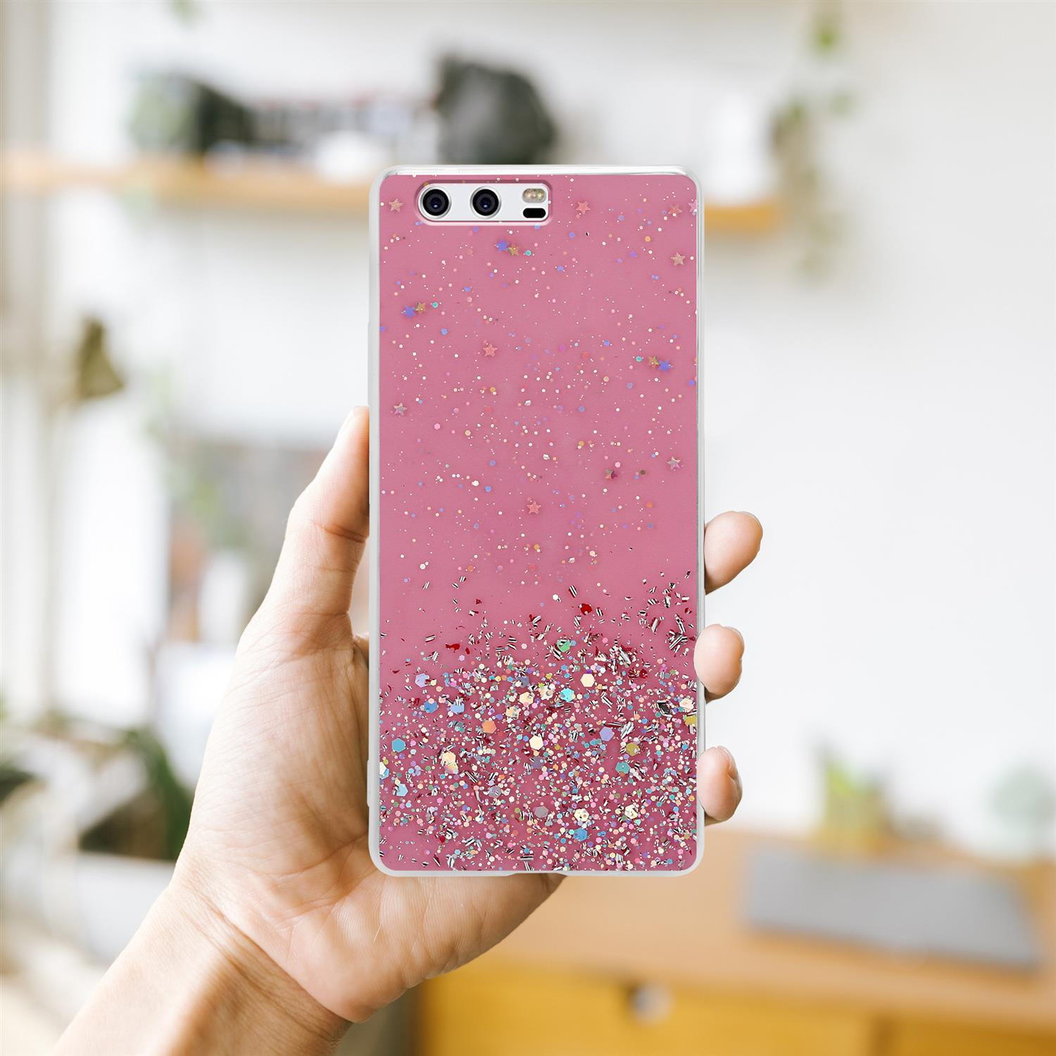 Eine Hand hält eine rosa Handyhülle mit Glitzer. Das Telefon befindet sich darin. Hintergrund: ein verschwommenes Büro.