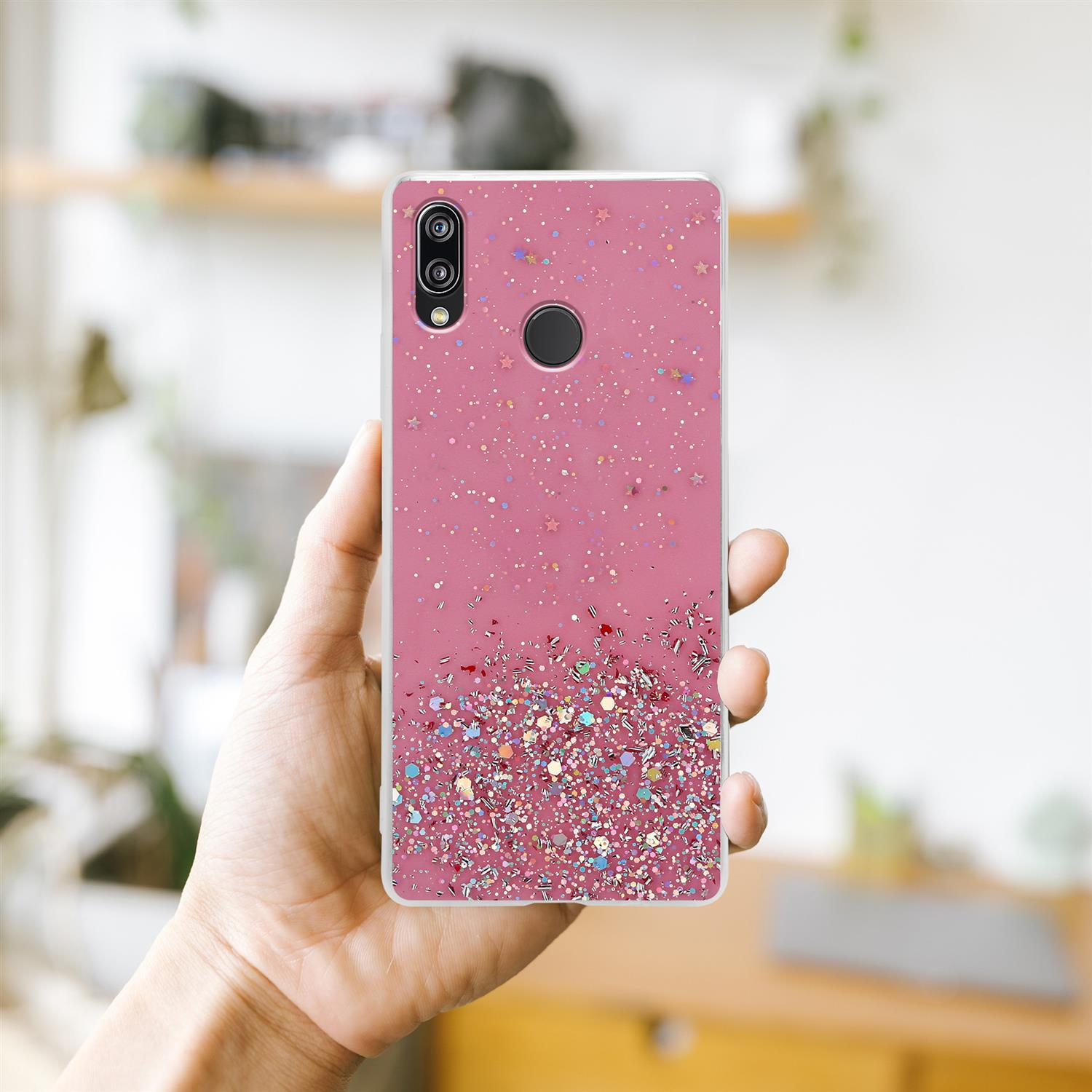 Eine Hand, die eine rosa Handyhülle mit Glitzer hält. Der Hintergrund ist unscharf.