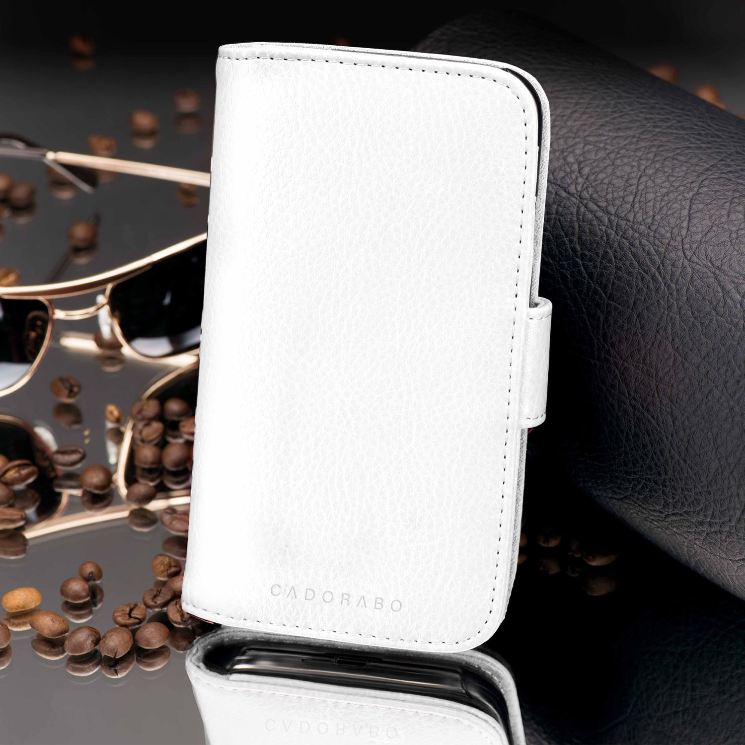 Weiße Leder-Handyhülle mit dem Wort "CADORABO" und Kaffeebohnen auf einer reflektierenden Oberfläche.