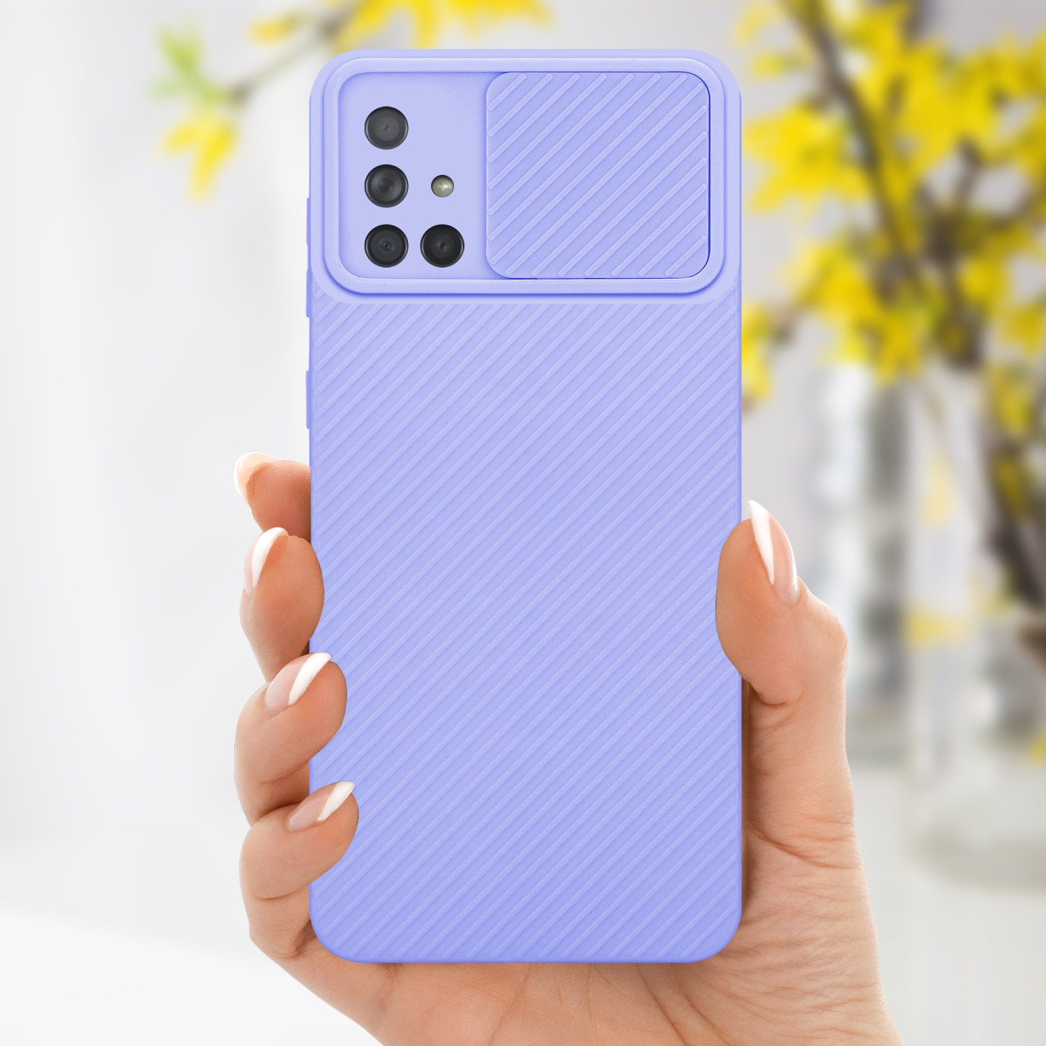 Eine Hand, die eine lila Handyhülle mit einer Kameraabdeckung hält. Der Hintergrund ist verschwommen, mit gelben Blumen.