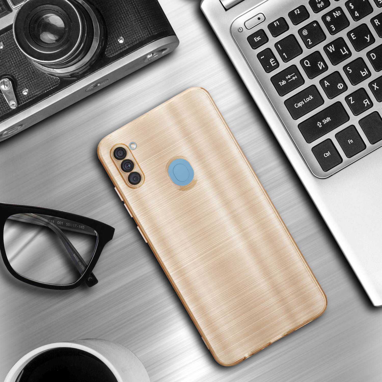 Una custodia dorata per telefono su una scrivania, con un laptop, una fotocamera e occhiali accanto.