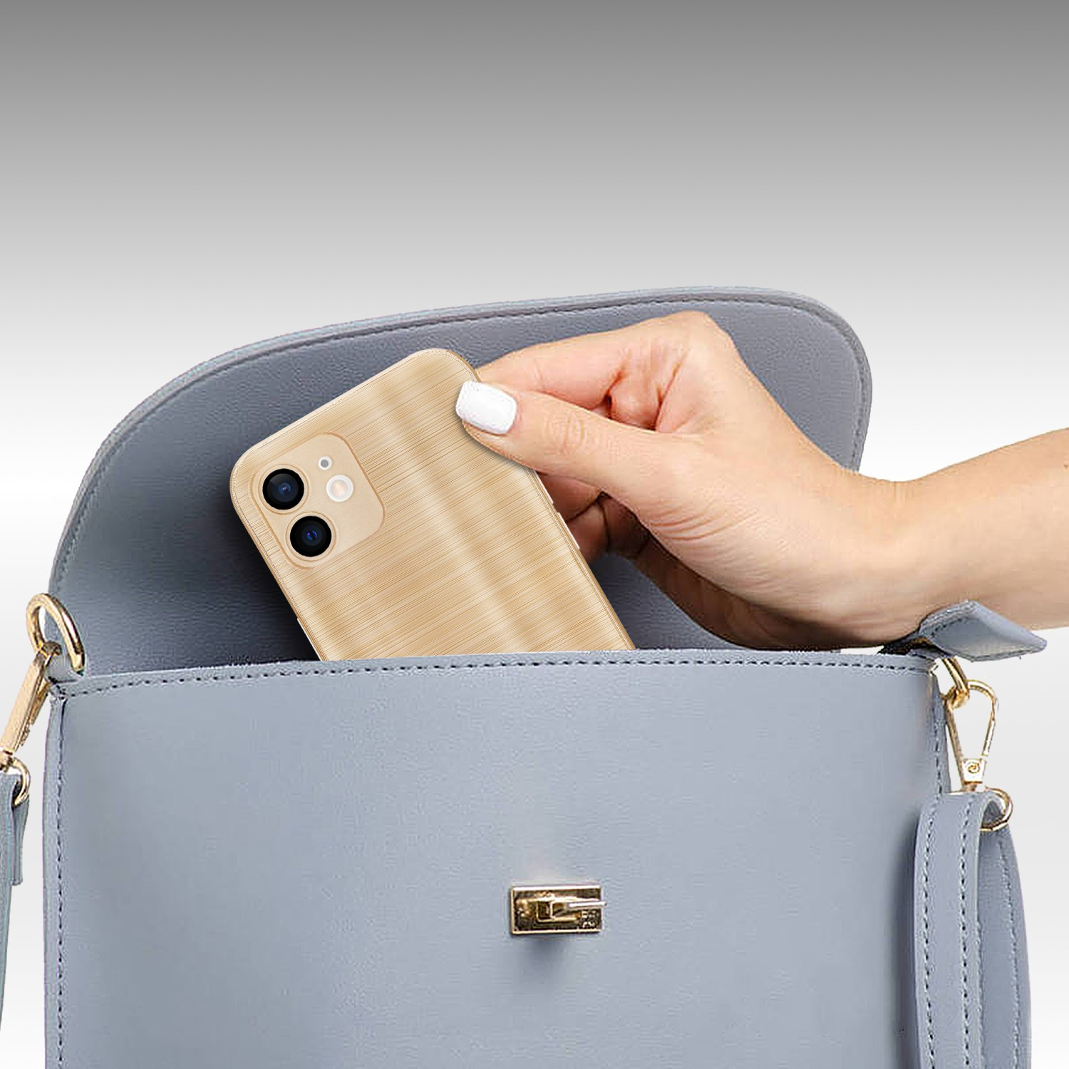 Mano che mette il telefono in una borsa blu. Il telefono è in una custodia dorata. La borsa è grigia.