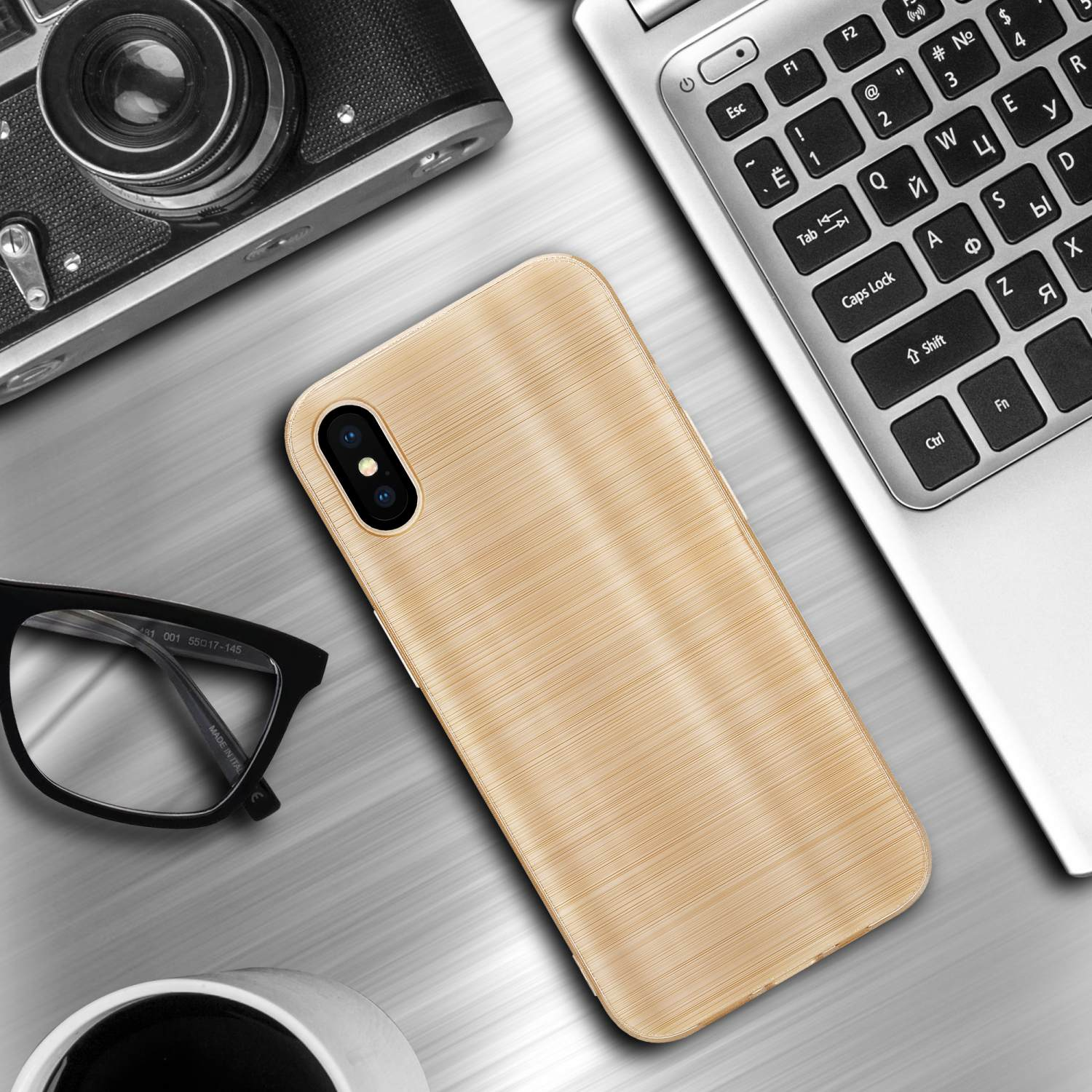 Custodia per telefono dorata effetto metallo spazzolato su scrivania con laptop e altri oggetti.