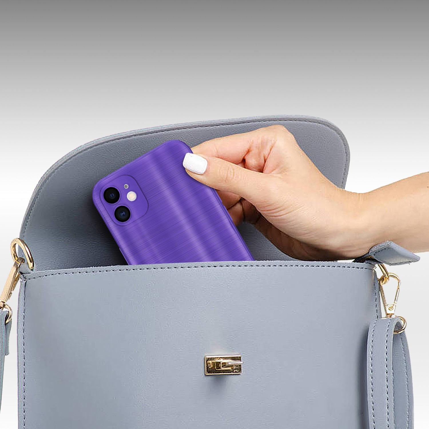 Eine Hand hält ein lila Telefon in einer grauen Handtasche. Die Handtasche ist geöffnet.