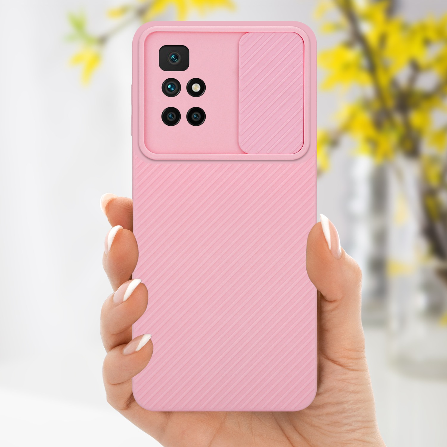 Mano che tiene una custodia rosa per telefono con una copertura per la fotocamera. Fiori gialli sullo sfondo.