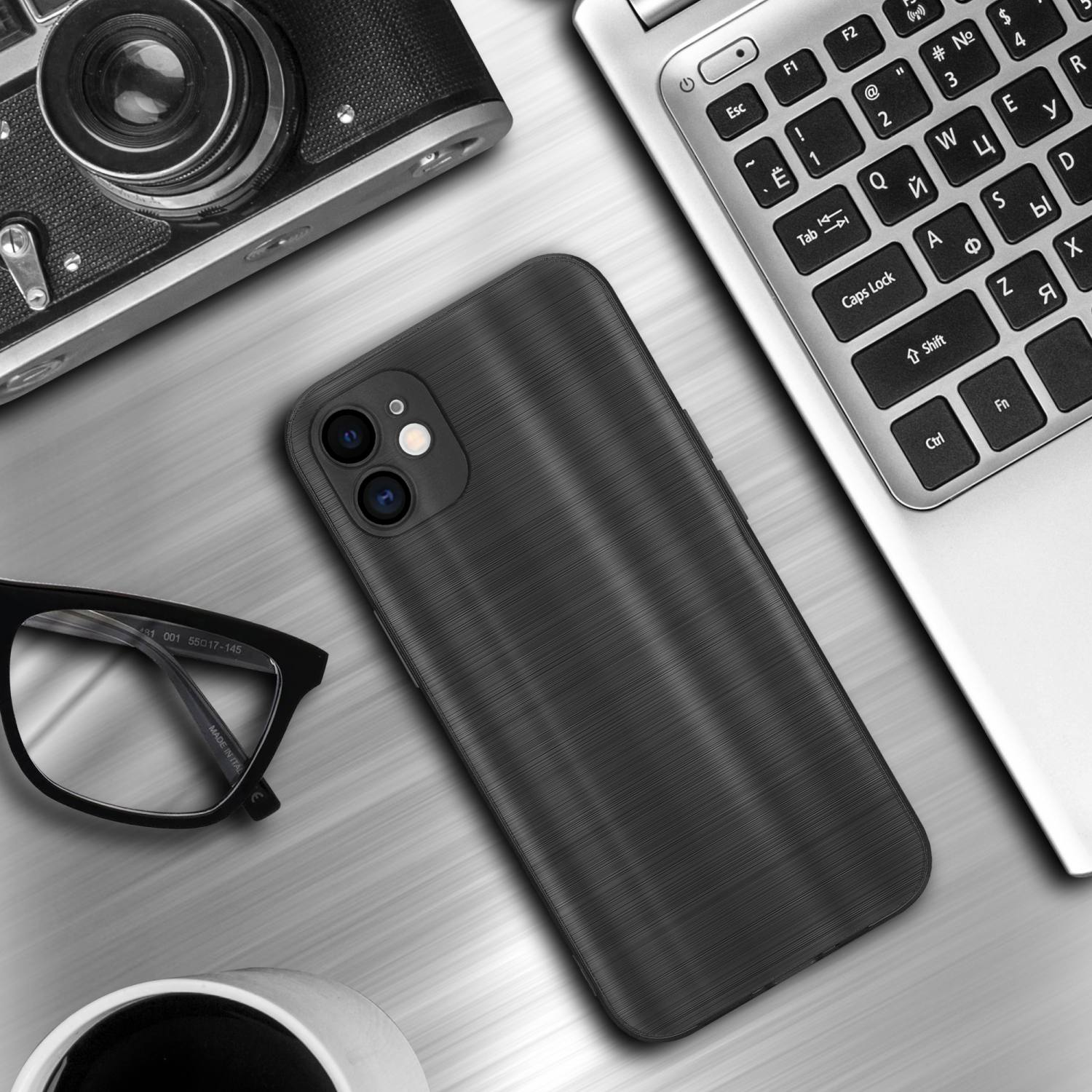 Custodia per telefono su una scrivania, accanto a un laptop, occhiali e una tazza. La custodia ha un aspetto di metallo spazzolato.