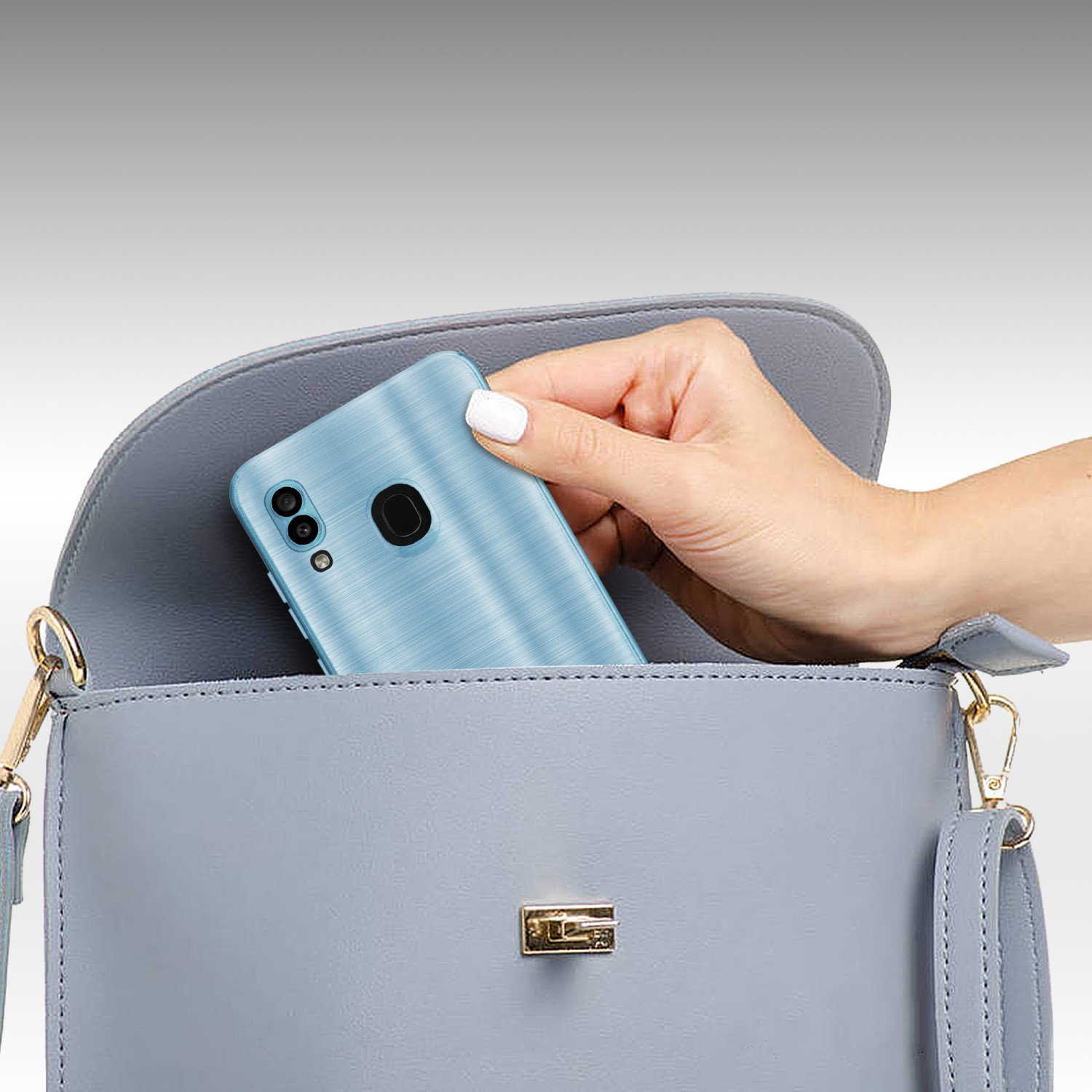Una mano che tiene un telefono blu, con una fotocamera, fuori da una borsa grigia. Lo sfondo è grigio chiaro.