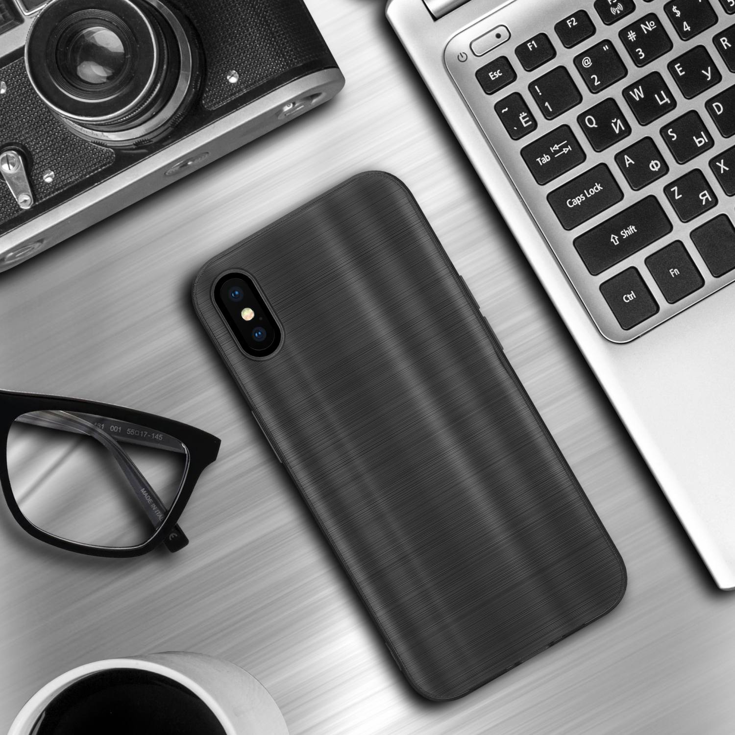Custodia per telefono nera su un tavolo, vicino a una fotocamera, occhiali e un laptop. La custodia è sul tavolo.