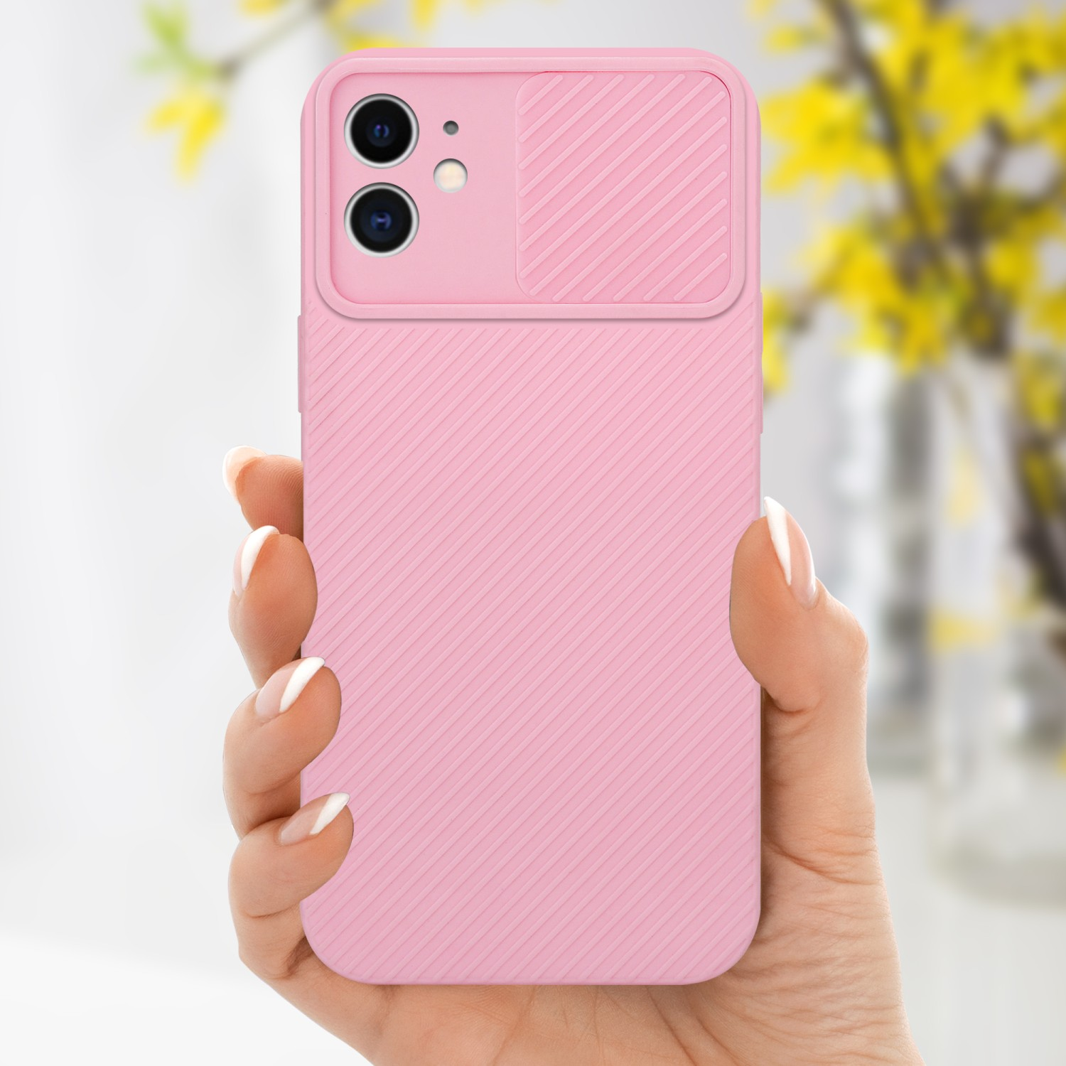 Custodia rosa per telefono con copertura della fotocamera tenuta da una mano. Fiori gialli sullo sfondo.