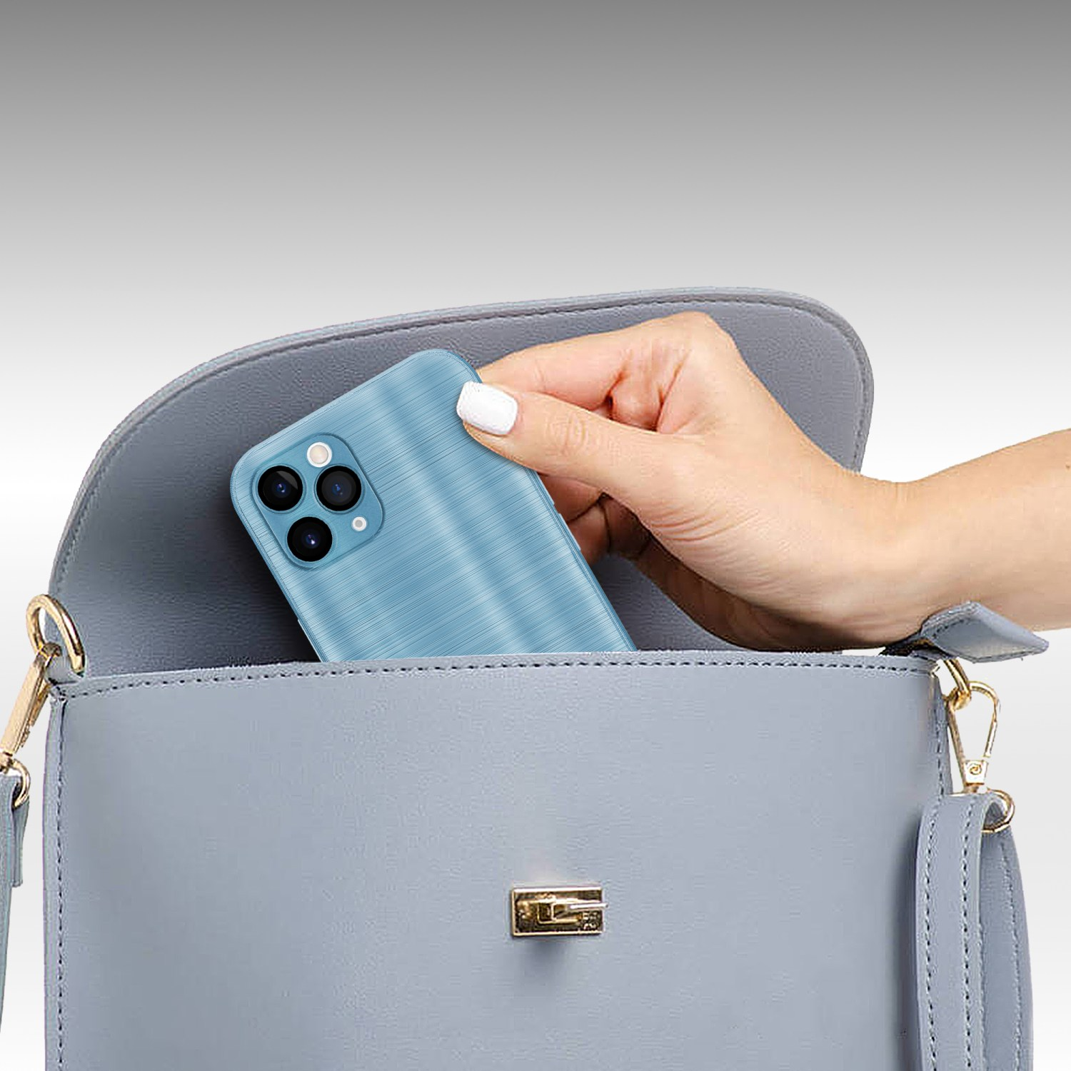 Hand legt eine blaue Handyhülle in eine graue Handtasche. Blaue Handyhülle mit strukturierter Oberfläche.