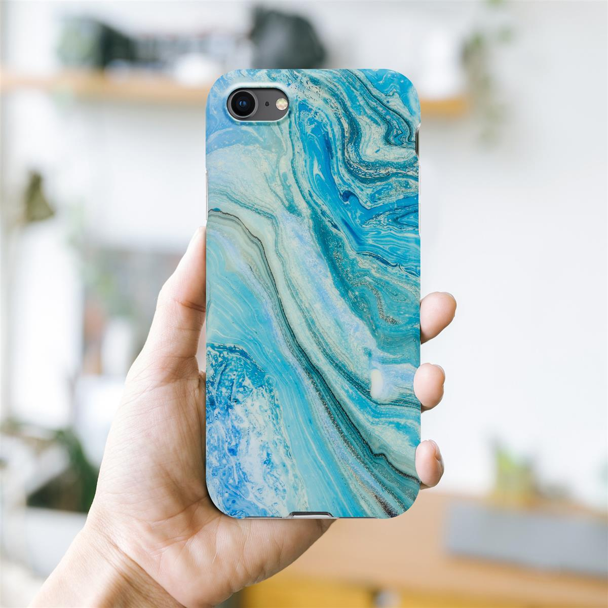 Mano che tiene il telefono con custodia in marmo blu e bianco. Sfondo bianco.