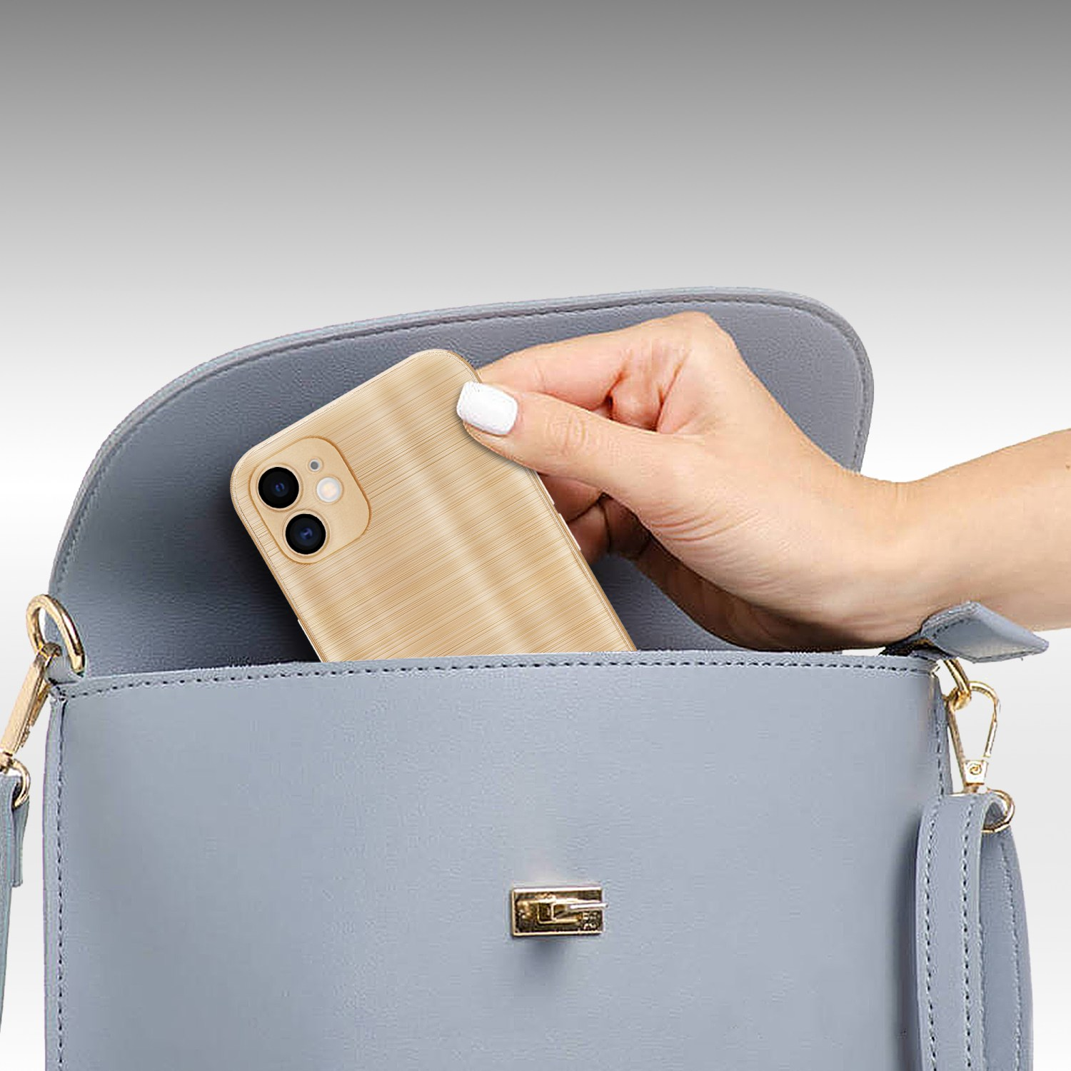 Una mano mette un telefono in una borsa azzurra. La custodia del telefono è dorata con motivo legno.