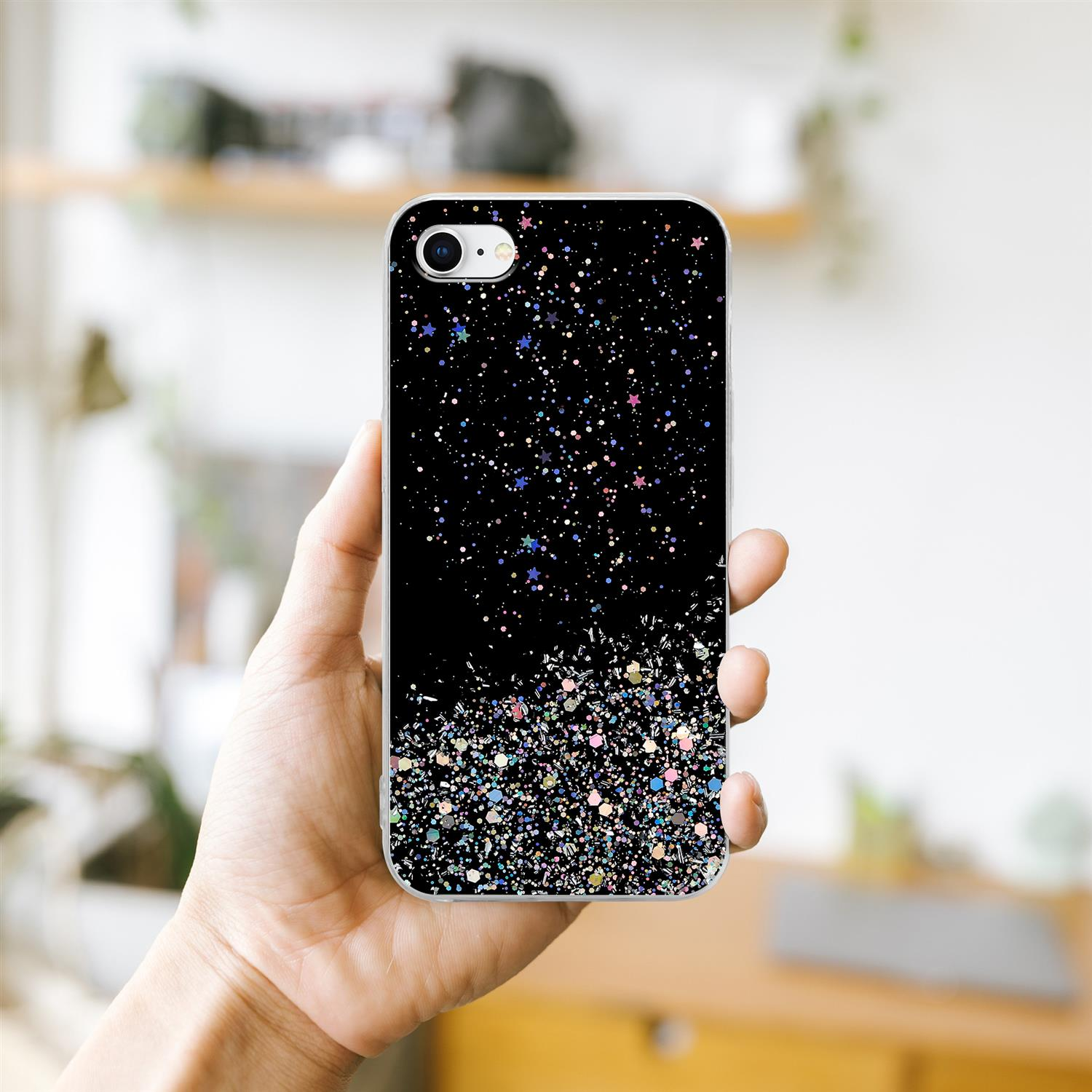 Eine Hand, die ein Telefon mit einer schwarzen Glitzerhülle hält. Die Hülle hat bunten Glitzer am unteren Rand, mit schwarzem Hintergrund.