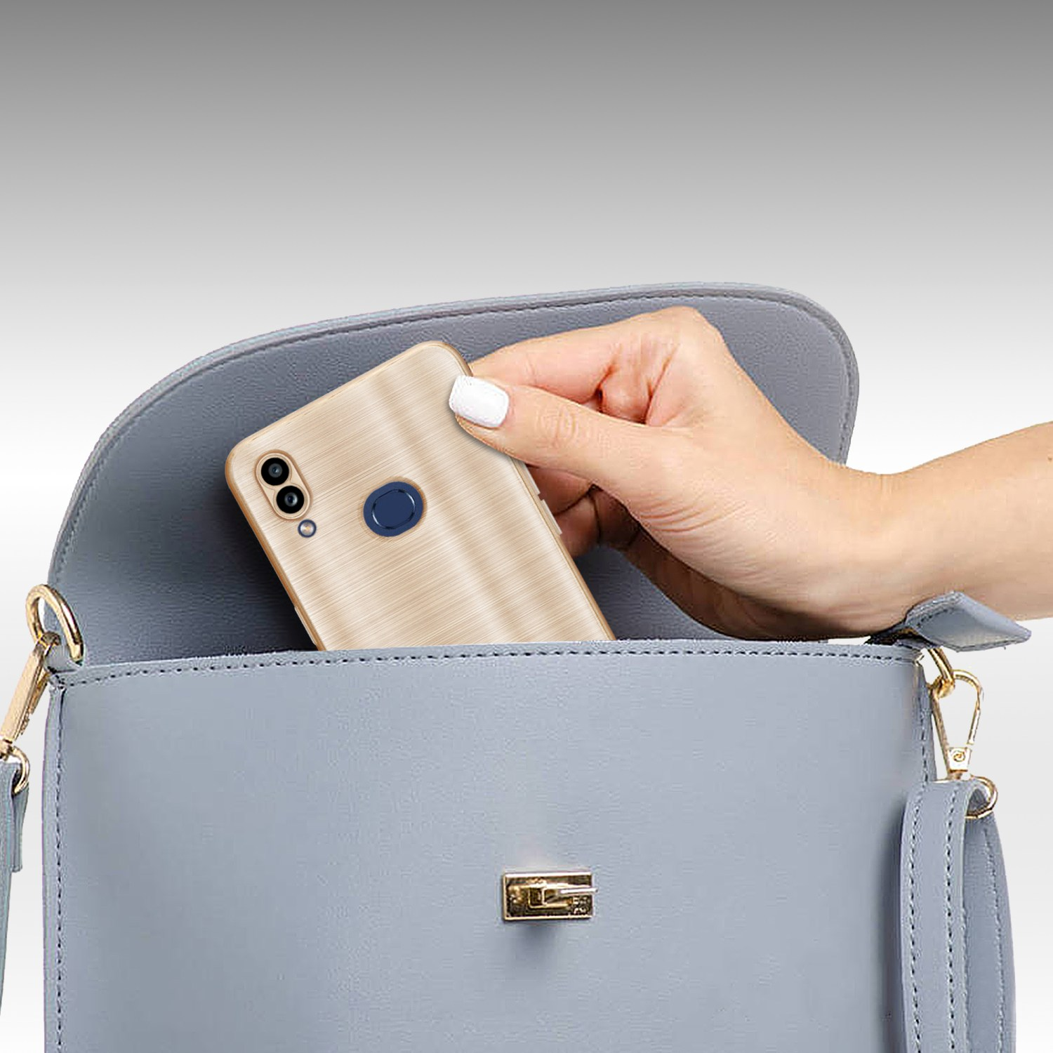 Una mano mette un telefono in una borsa blu. La custodia del telefono è dorata con motivo legno.