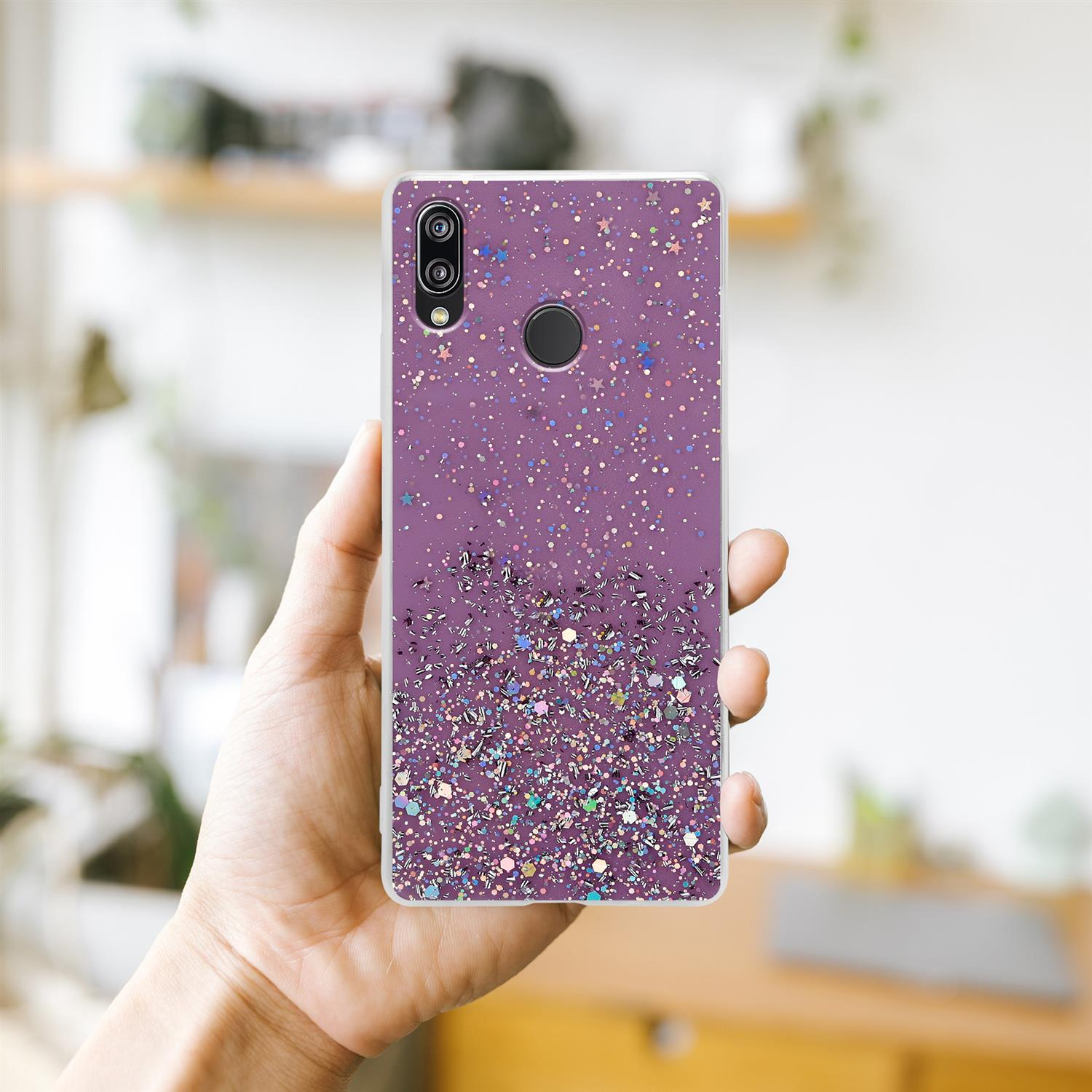 Hand hält eine lila Handyhülle mit Glitzer. Hintergrund mit Regalen.