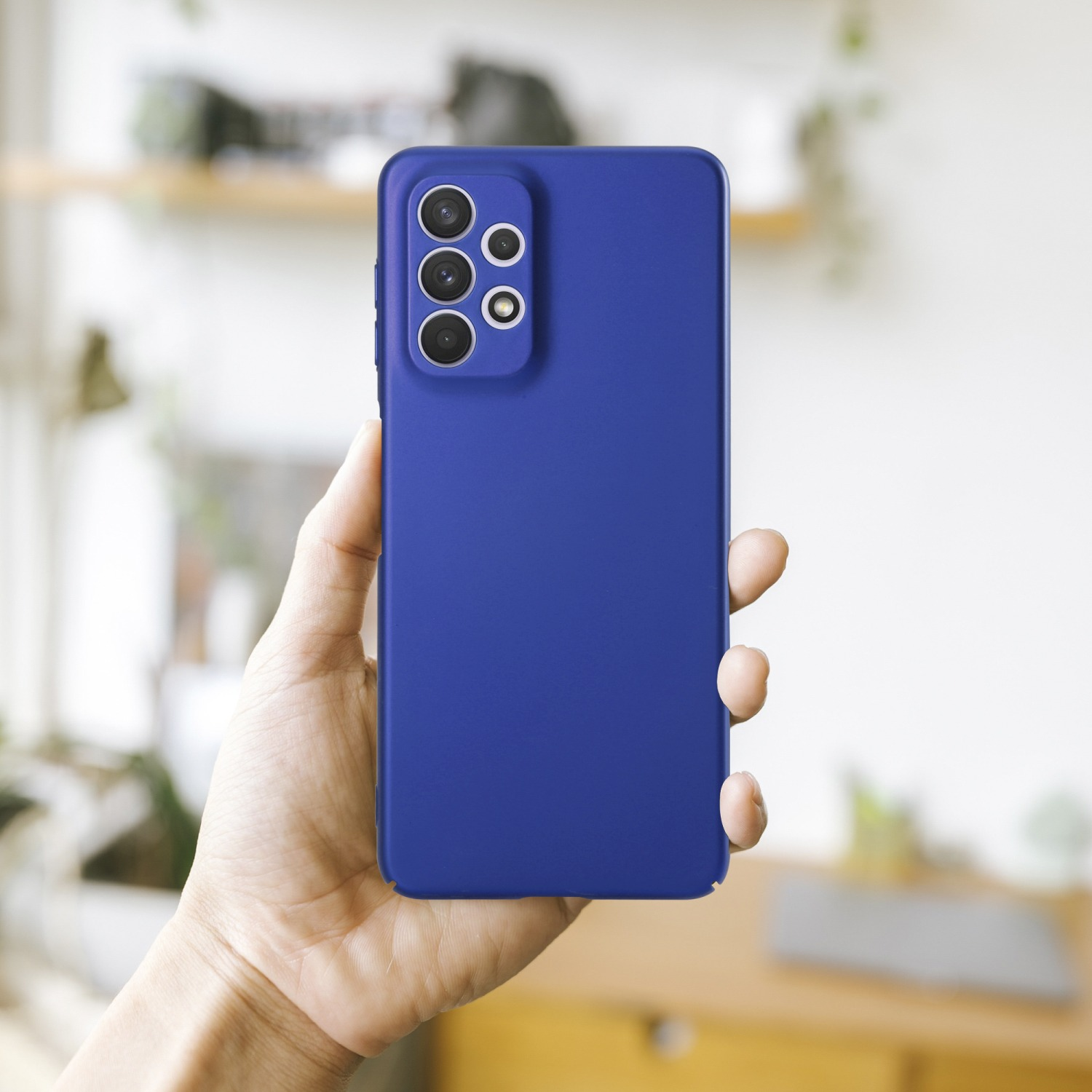 Blaue Handyhülle. Eine Hand hält die Handyhülle. Verschwommener Hintergrund.
