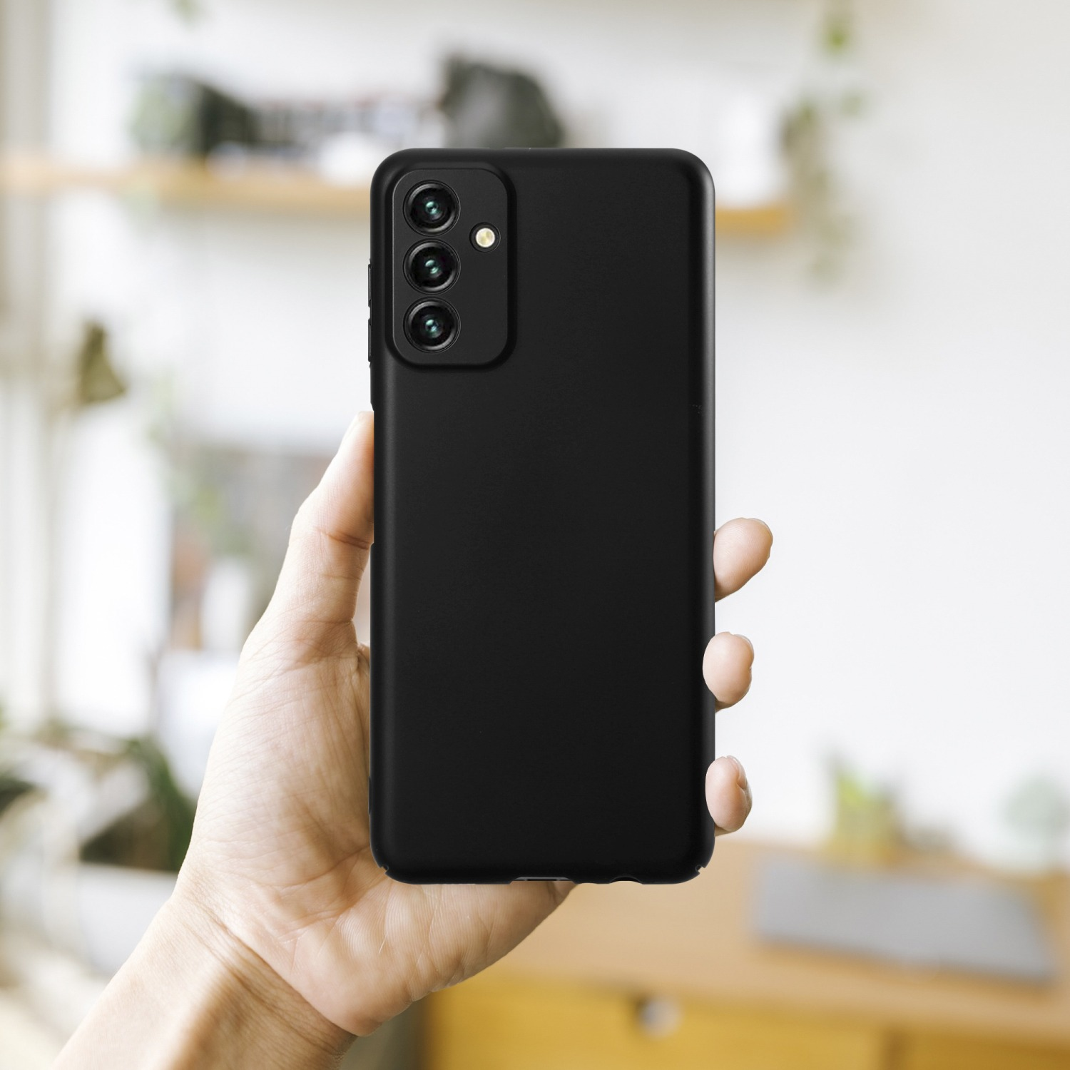 Schwarze Handyhülle in der Hand. Das Telefon hat drei Kameralinsen.