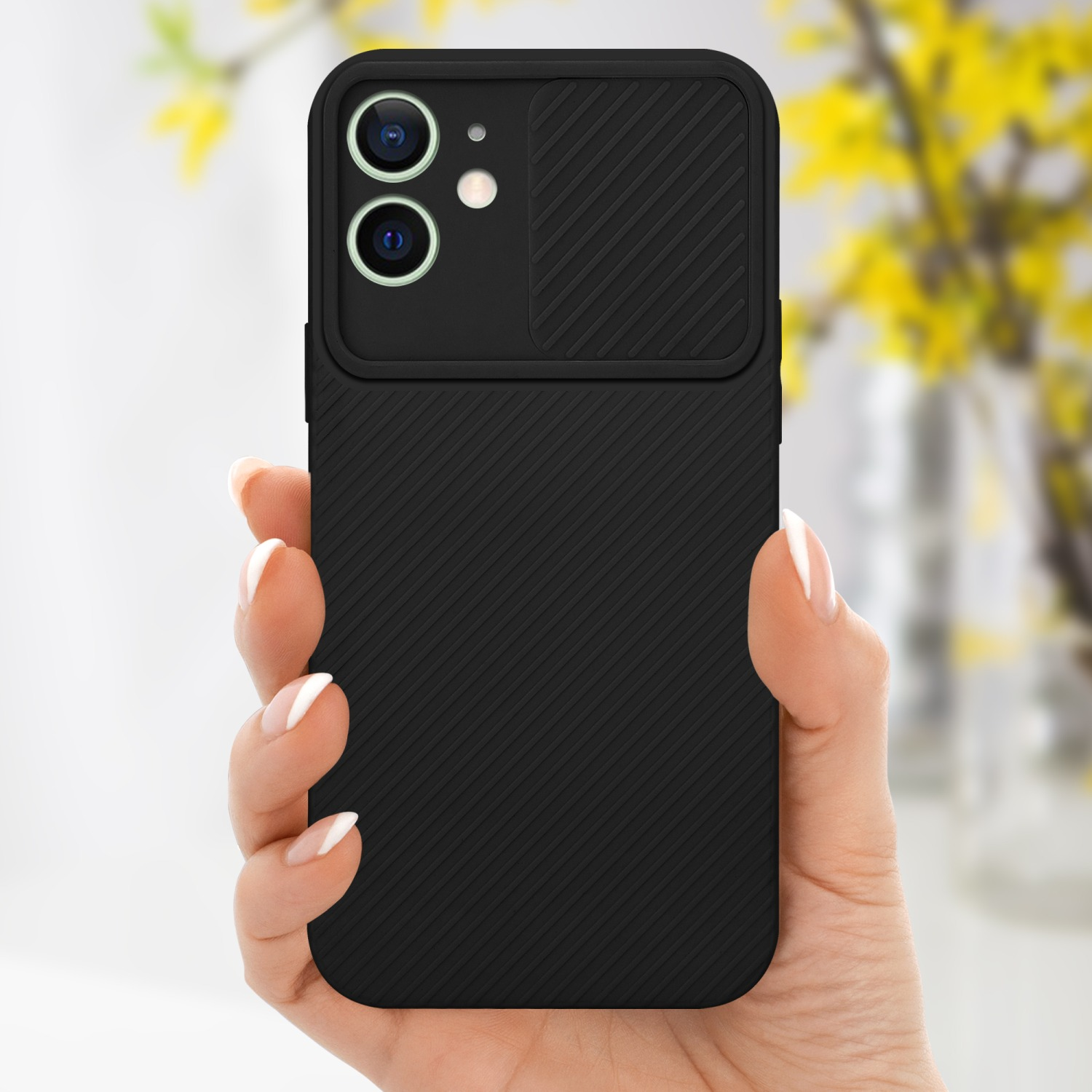 Hand hält schwarze Handyhülle mit Kameraabdeckung, gelbe Blumen im Hintergrund.