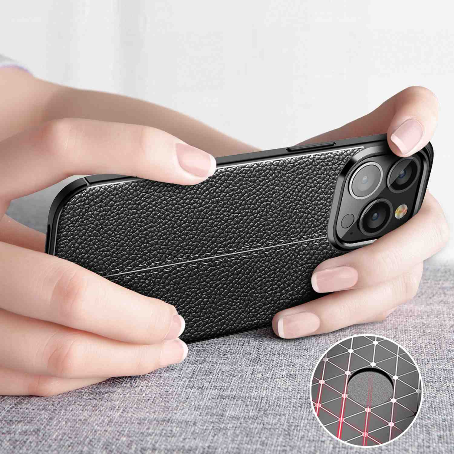 Eine Person hält ein schwarzes Telefon mit einem genähten Lederdesign.