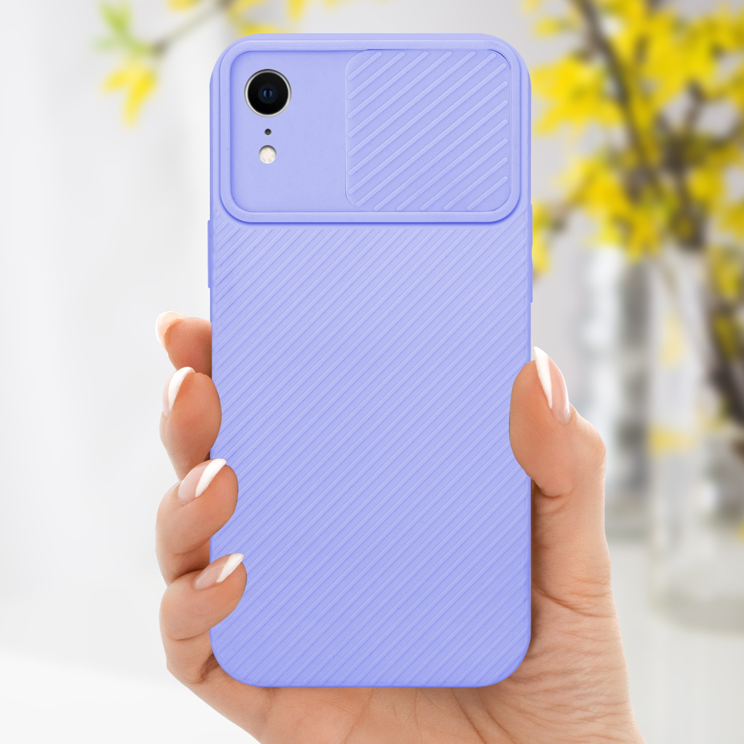 Eine Hand hält eine lila Handyhülle mit Kameraabdeckung, gelbe Blumen im Hintergrund.