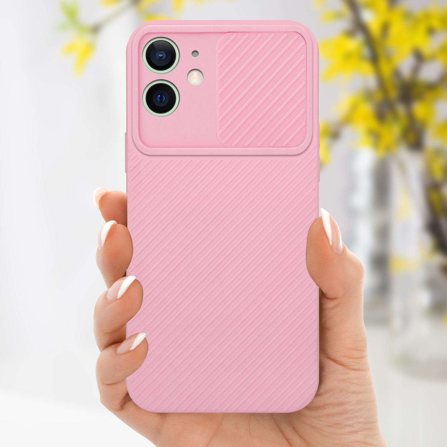 Hand hält eine rosa Handyhülle. Die Hülle hat eine Kameraabdeckung. Gelbe Blumen im Hintergrund.