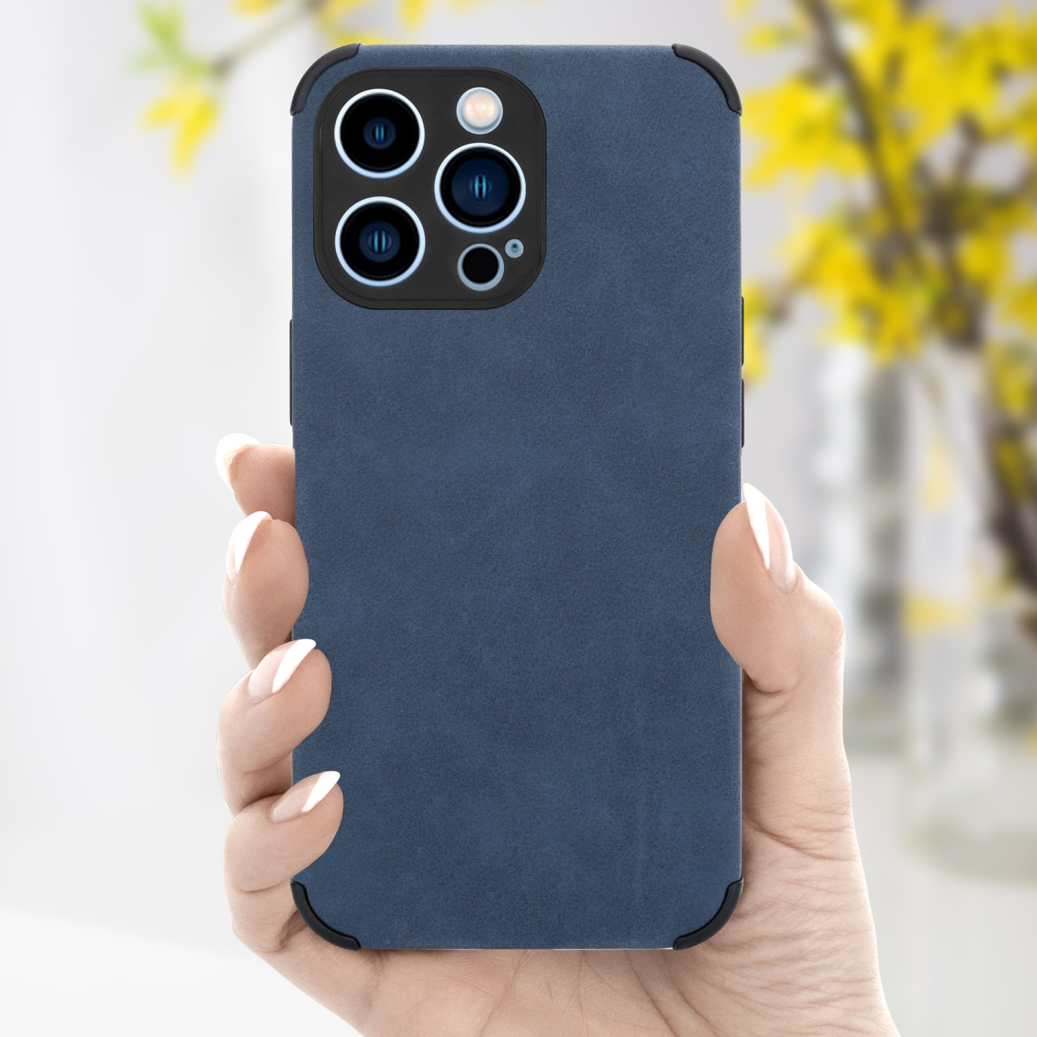 Hand hält blaue Handyhülle. Hülle hat Dreifachkamera und schwarze Ränder. Gelbe Blumen im Hintergrund.
