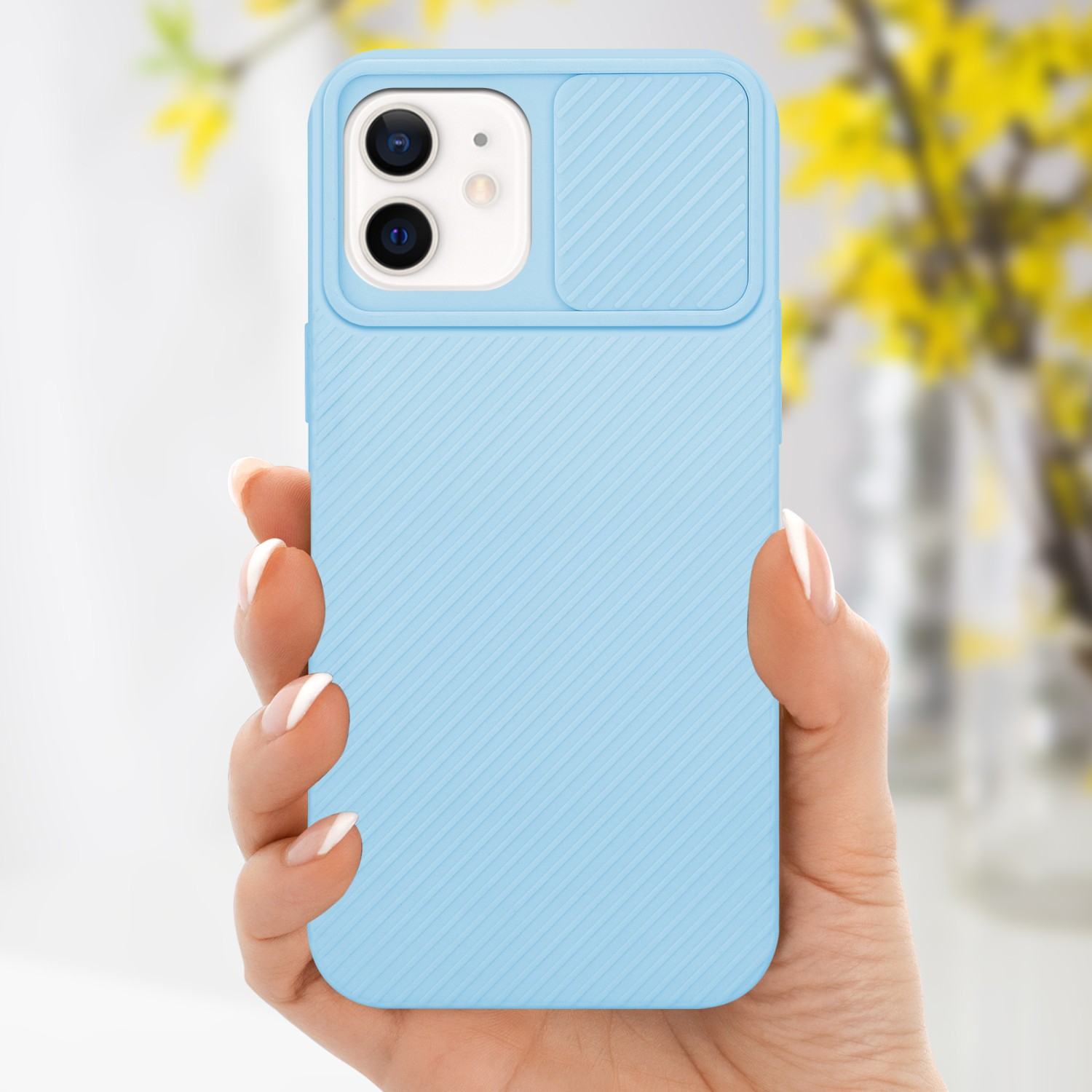 Hand hält eine blaue Handyhülle mit Kameraabdeckung. Verschwommene gelbe Blumen im Hintergrund.