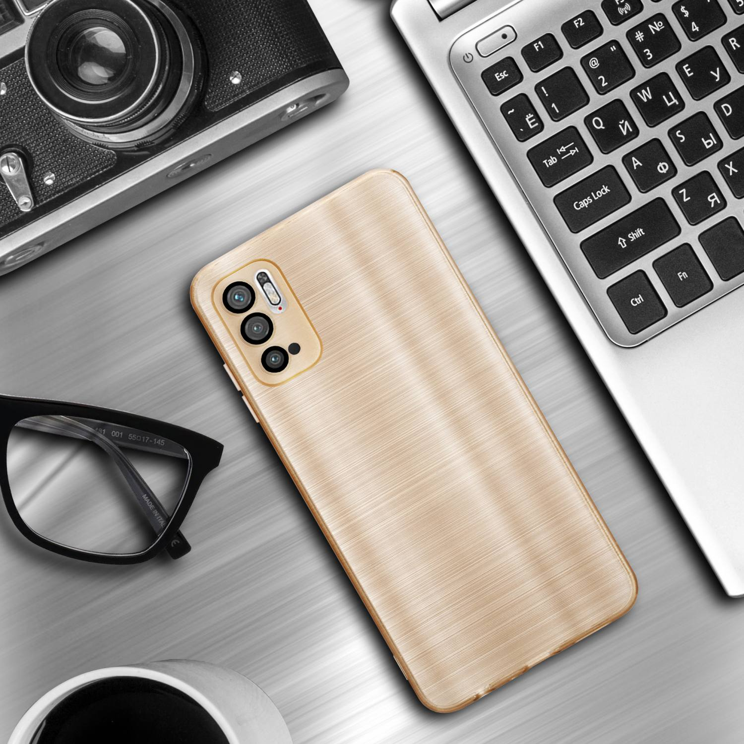 Una custodia dorata per telefono su una tastiera d'argento per laptop, con una fotocamera, occhiali e una tazza.